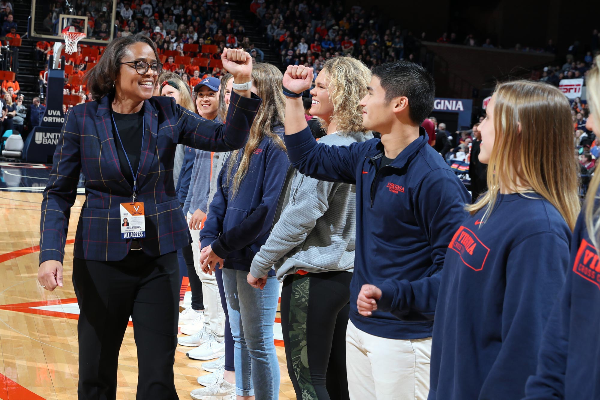 Carla Williams giving fist bumps to a line of students who are standing on the basketball court