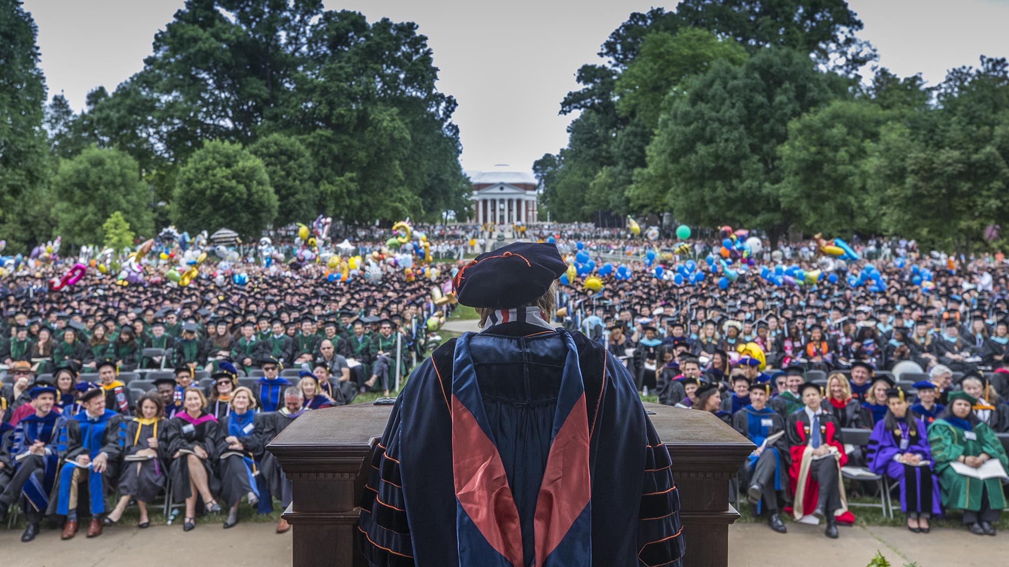 Person speaking to a crowd from a podium on stage on the Lawn at graduation