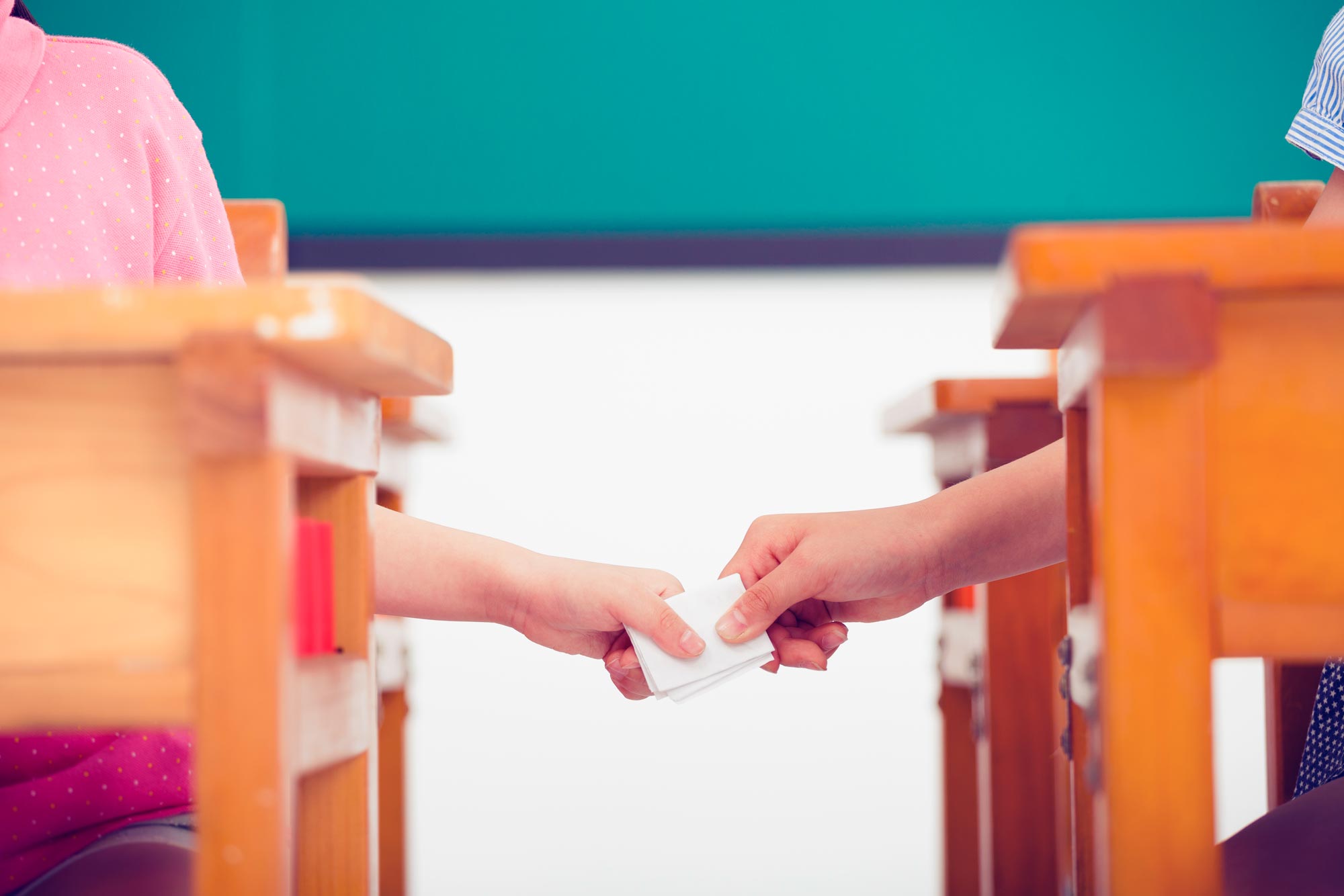 two kids passing a paper note in class