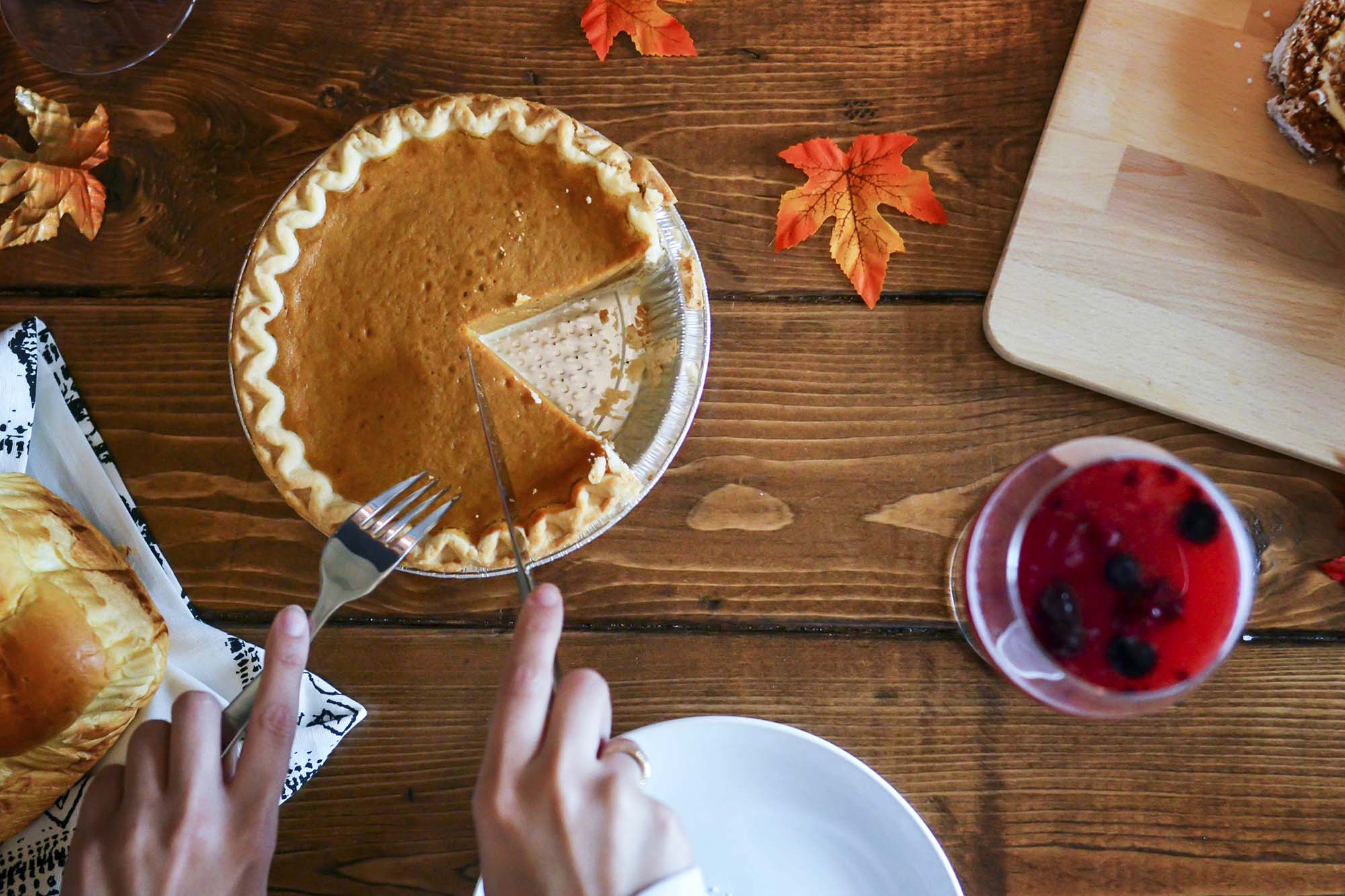 Person cutting a piece of pumpkin pie