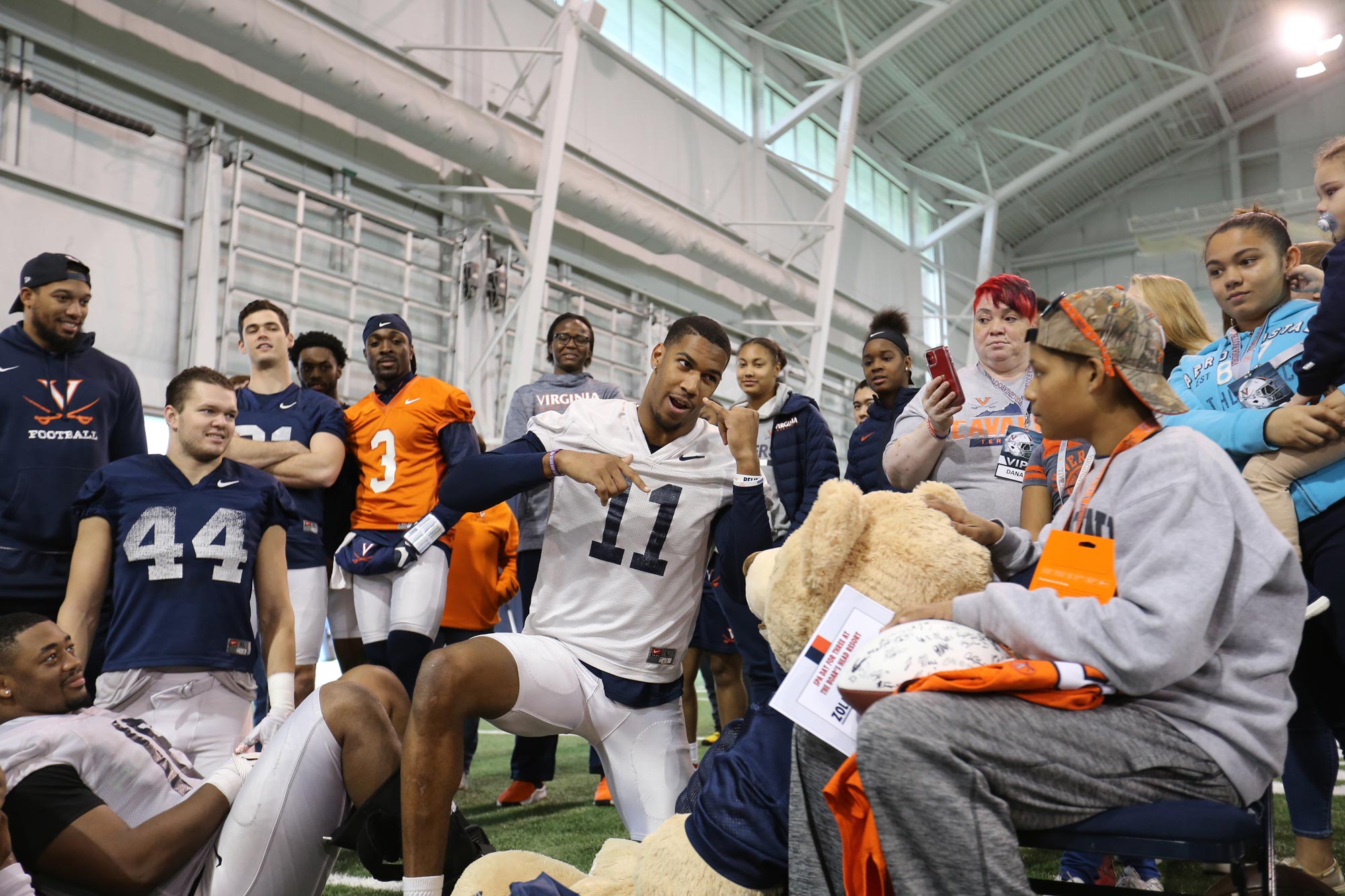 UVA football team talking to Thursdays special hero who is sitting in a chair