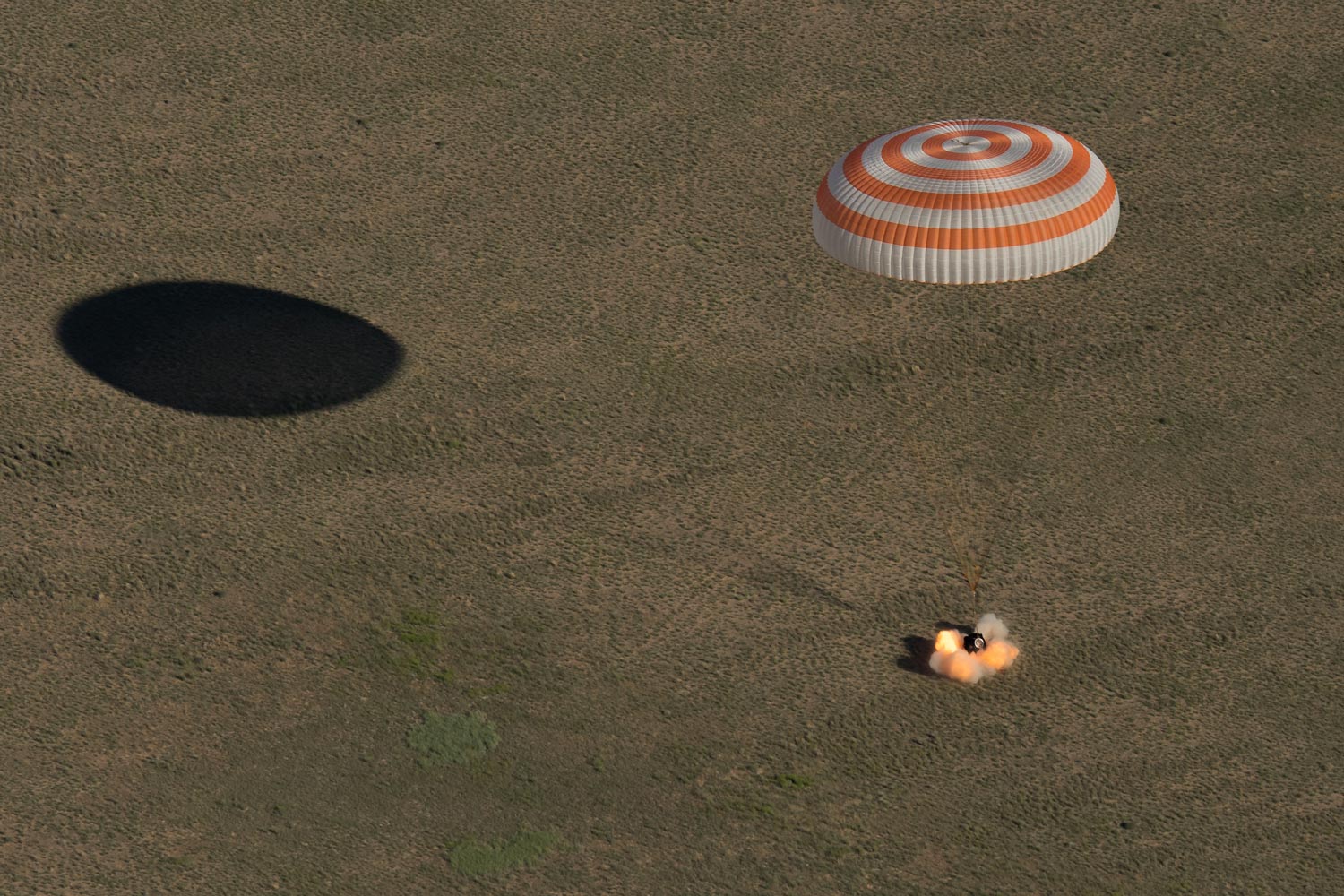 orange and white Parachute hangs above the tingle as it lands on the ground