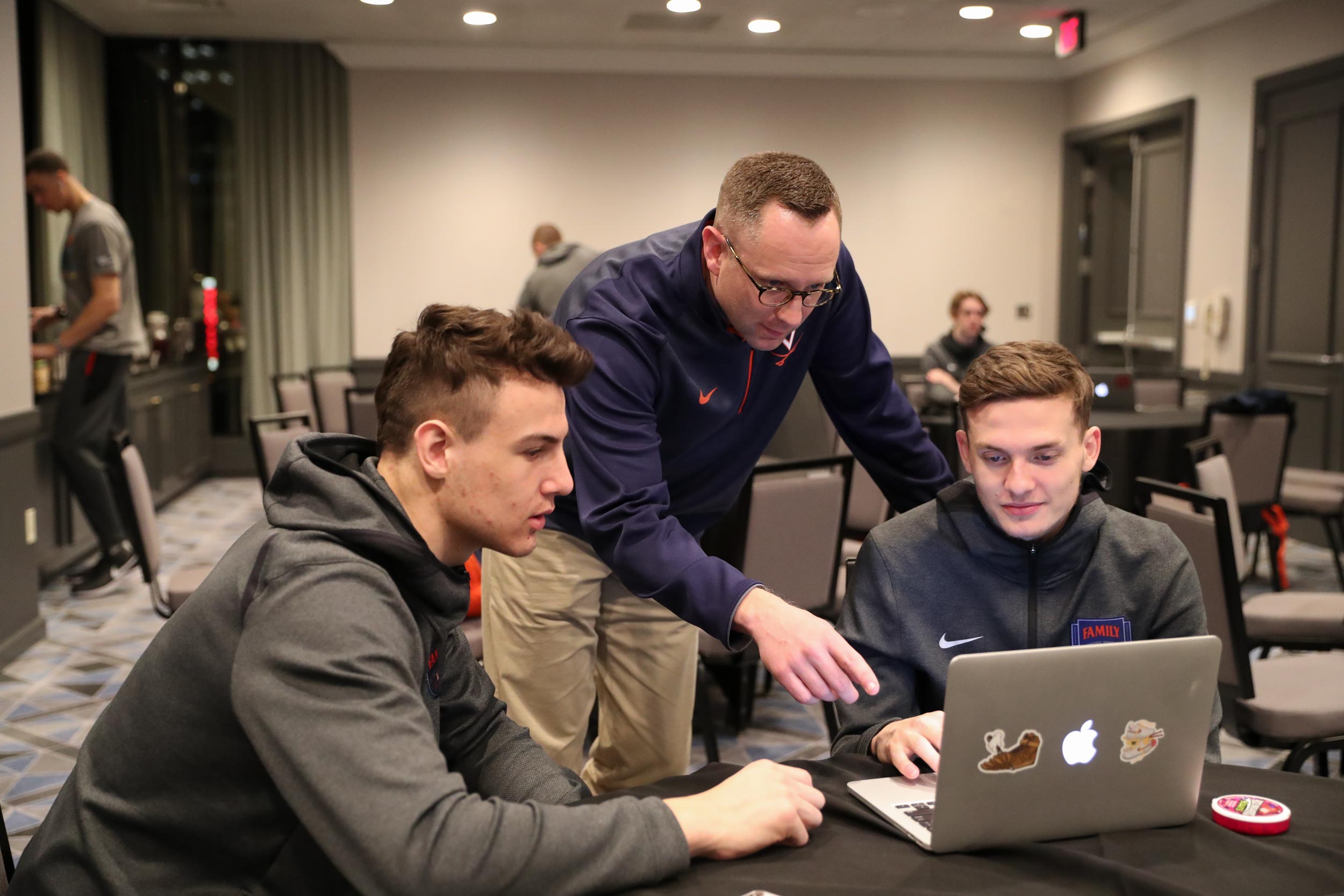 T.J. Grams, center, works with Francisco Caffaro, left, and Kyle Guy at a study hall Wednesday in Minneapolis. Grams helps players connect with professors and the academic resources they need to succeed. (Photo by Matt Riley, UVA Athletics)