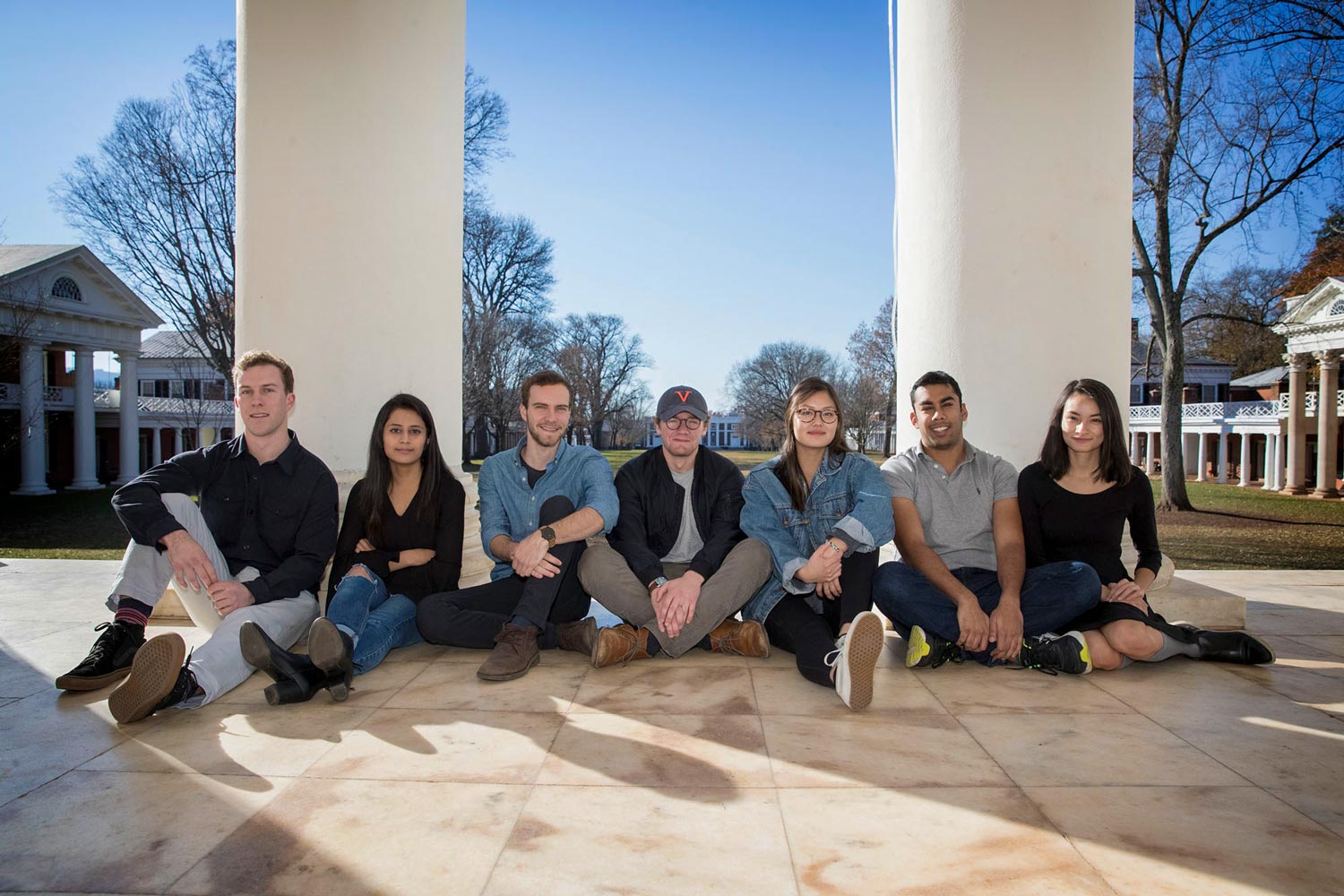 Charlie Tolleson, Nina Satasiya, Tyler Chartier, Andy Page, Anna Kuno, Yash Tekriwal and Amy McMillen sit together on the floor in front of the Rotunda entrance