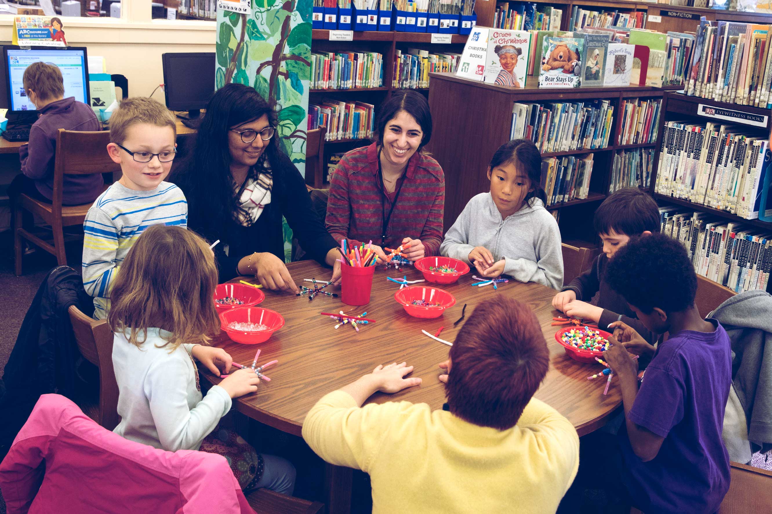Lajja Patel, and Darya Tahan, work with children on creative projects at a table