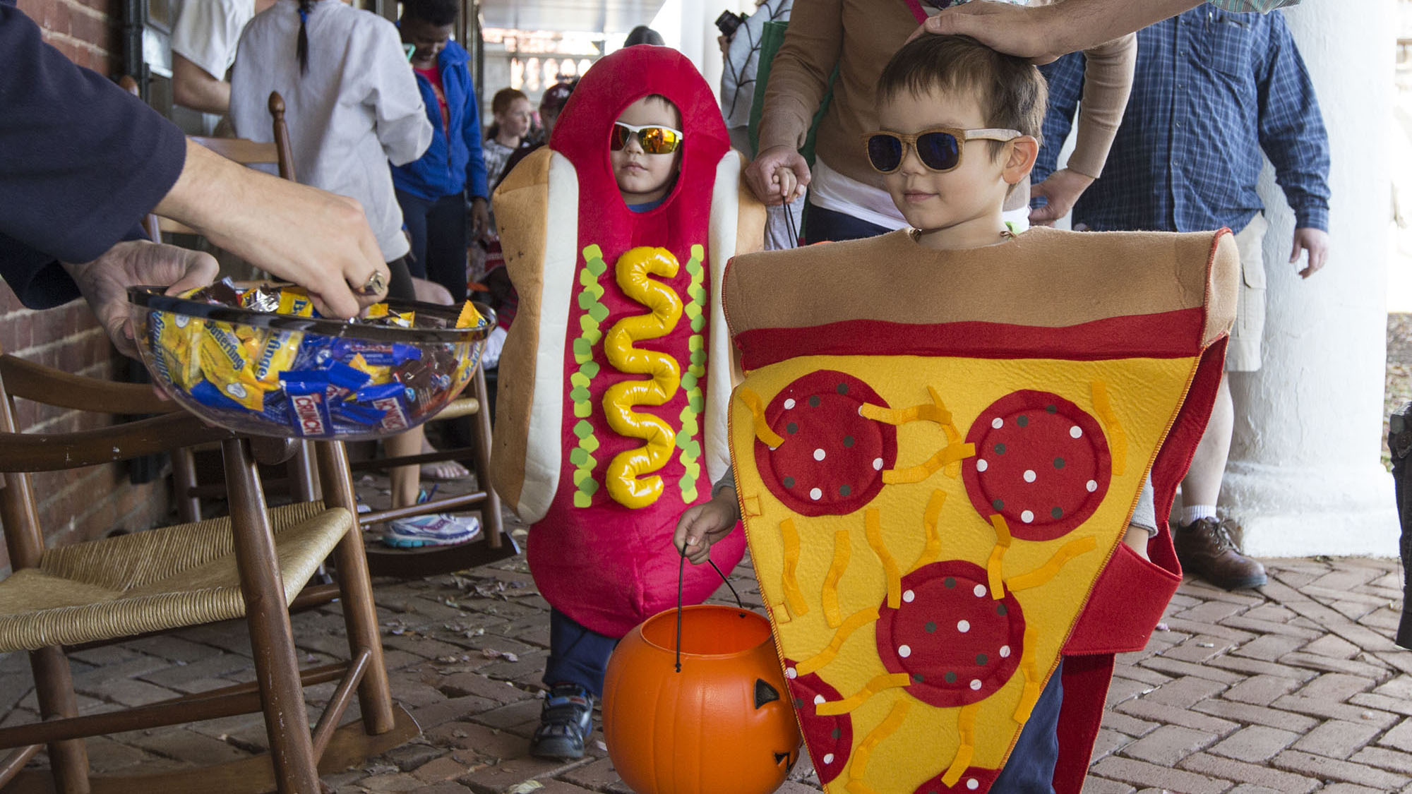 Little boys dressed up as pizza and a hotdog trick or treat on the lawn