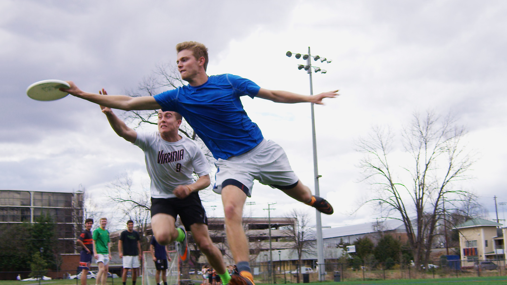 two people playing ultimate frisbee. One player tries to knock the frisbee out of their hand