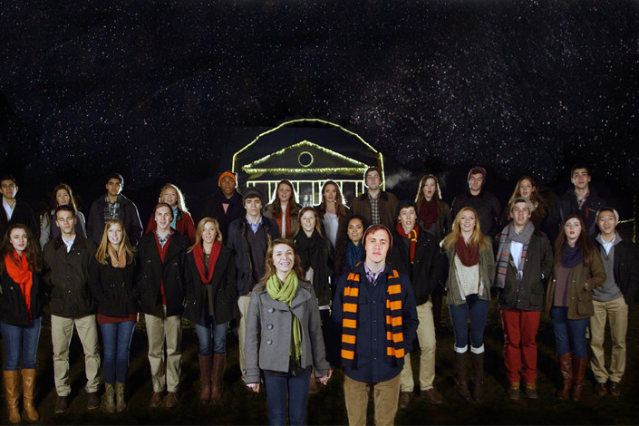 The Virginia sil'hoosettes and the Virginia Gentlemen stand together singing on a backdrop of a black starry sky and a light outlined Rotunda
