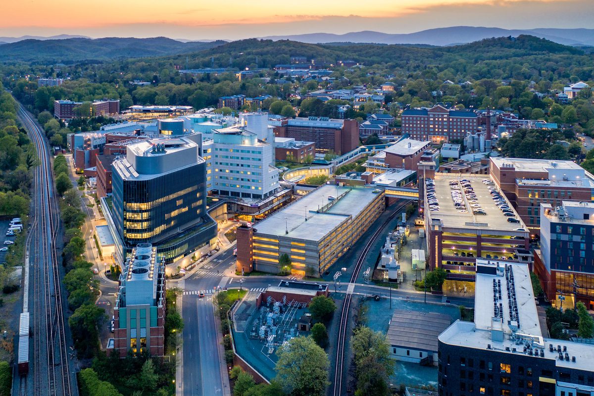 Arial view of the UVA Health Center Buildings with an orange and yellow sunset just above the blue ridge mountains