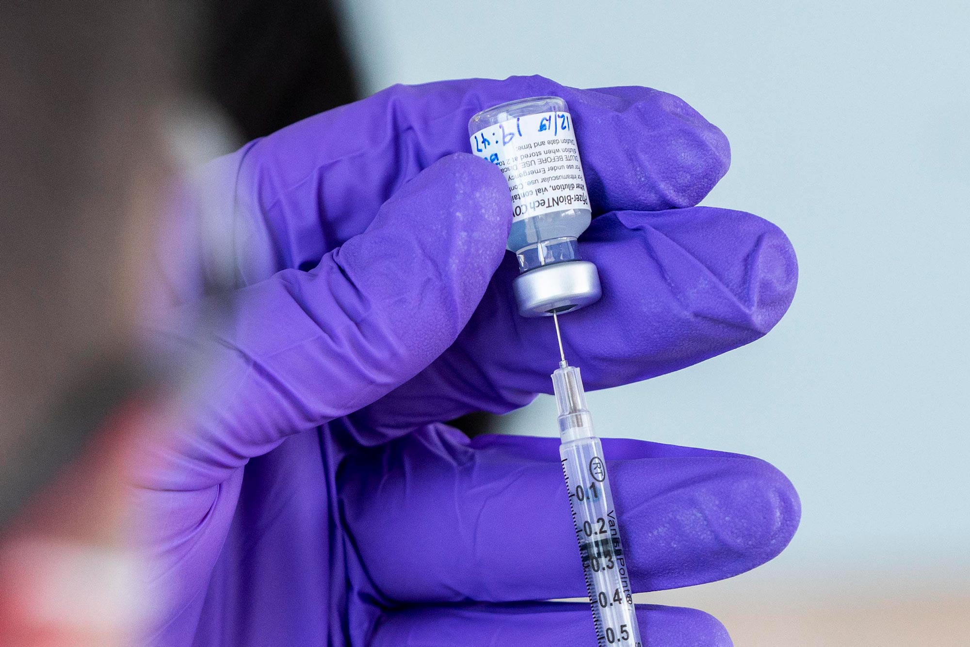 Healthcare professional drawing up a vaccine into a syringe 