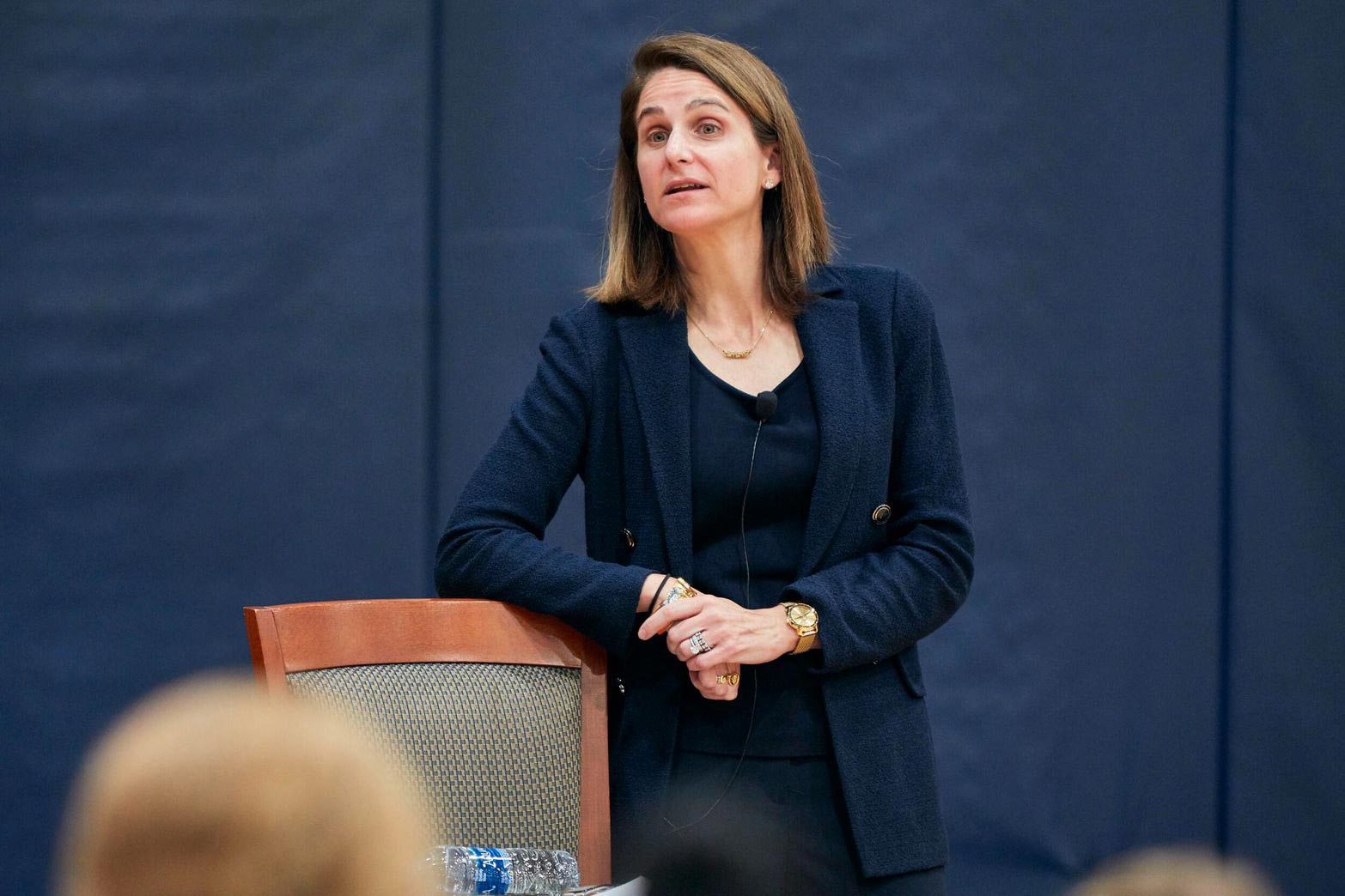 Michelle Cusimano Vachris leaning on the back of a chair while she talks to a crowd