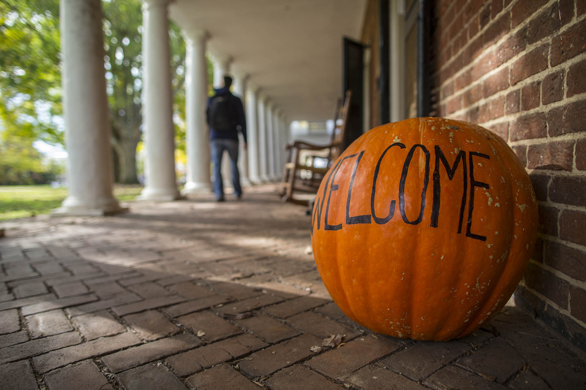 Pumpkin sitting next to a room on the Lawn with the word Welcome written on it. 