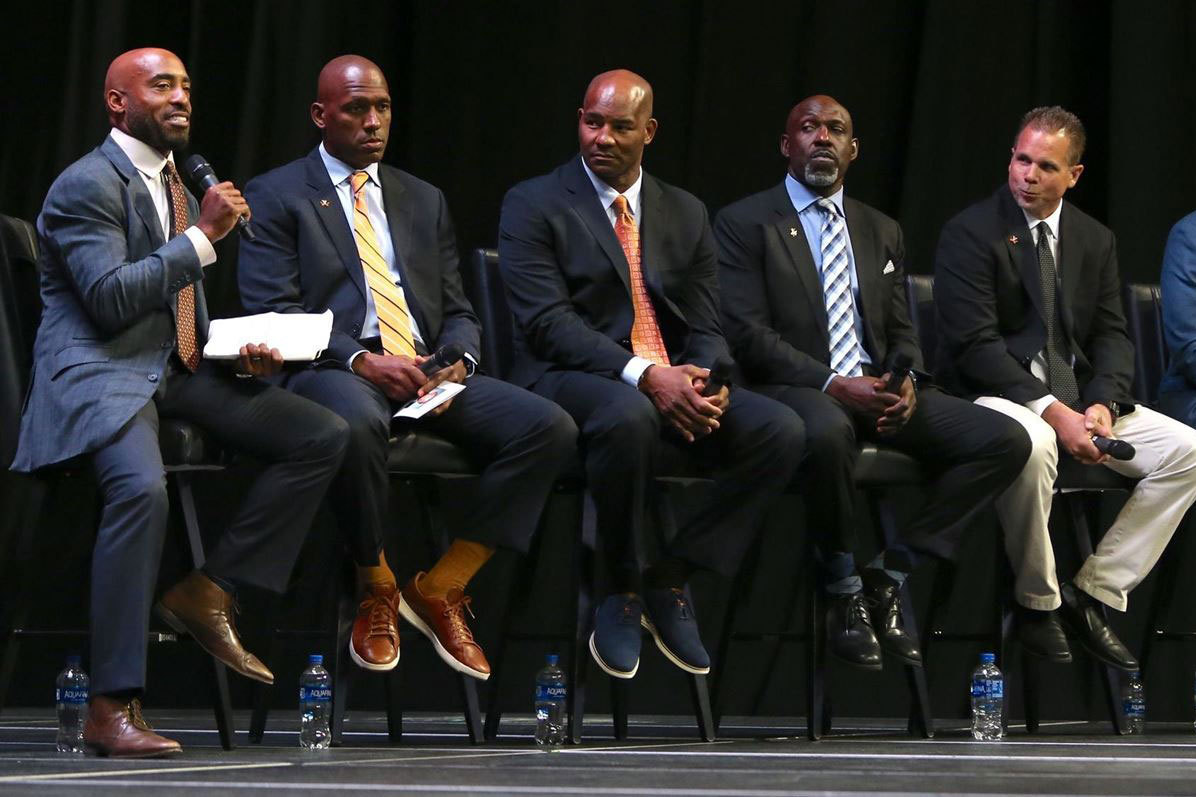 Alumnus Rondé Barber sits on stage with other men 
