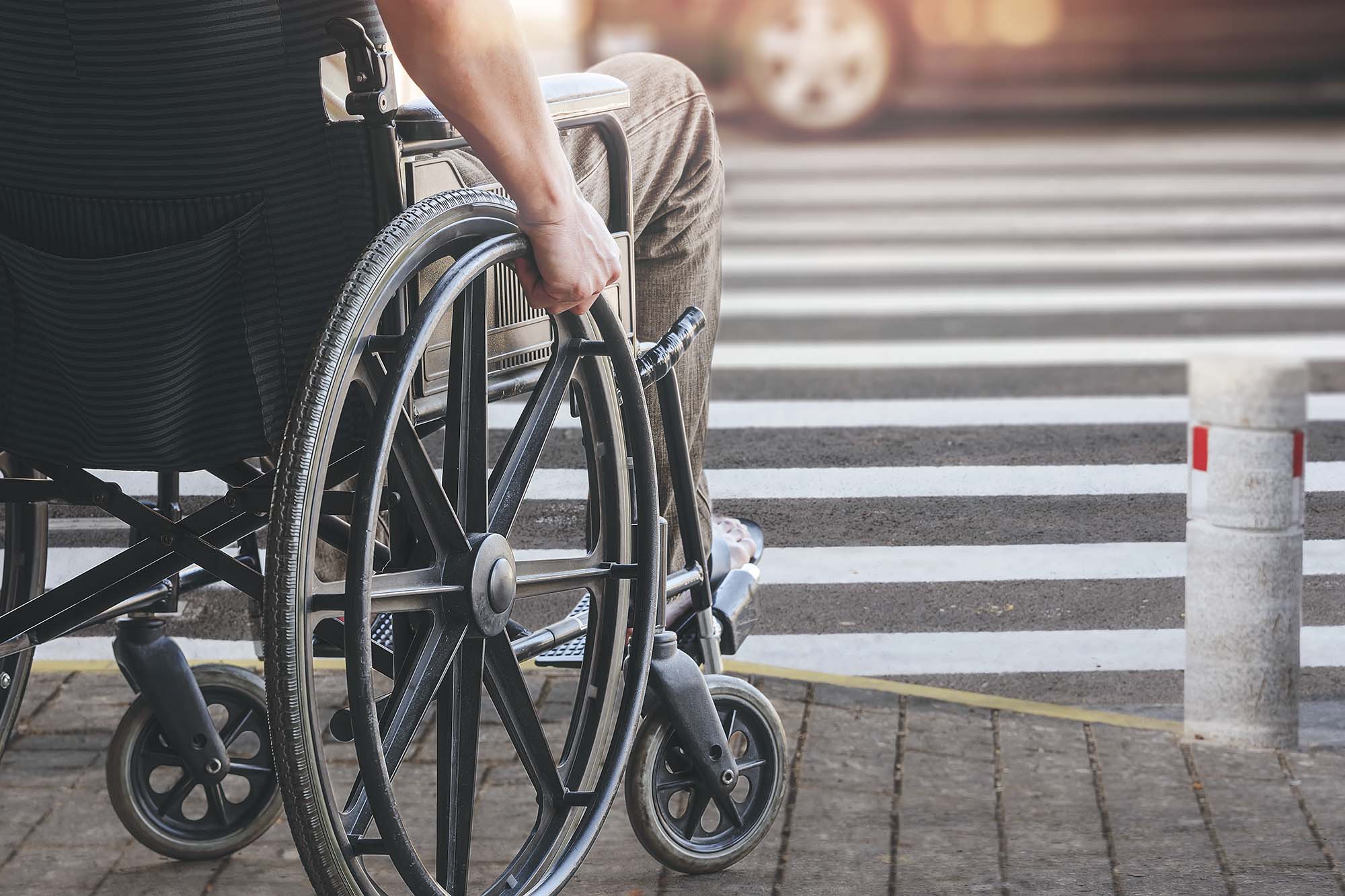 Wheelchair user sitting at a crosswalk waiting to cross