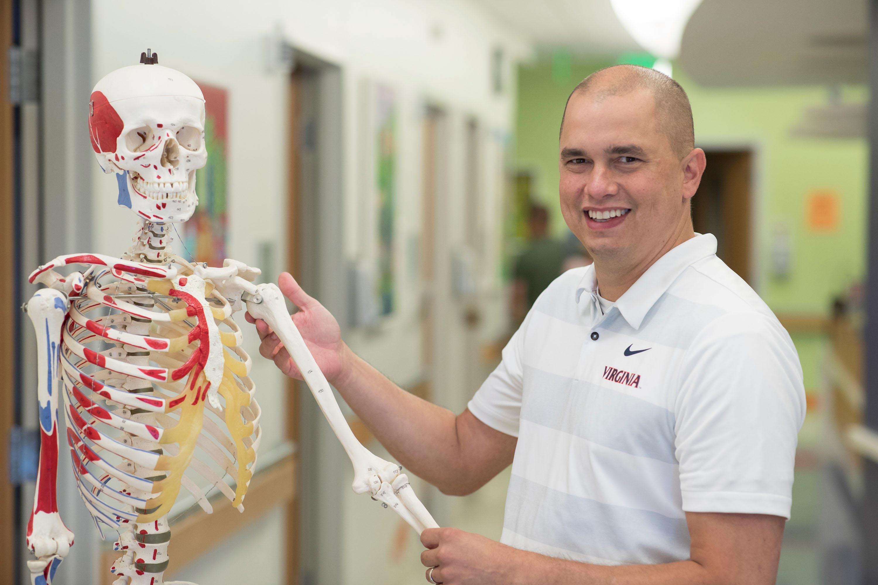 Dr. Winston Gwathmey stands with an educational bone skeleton