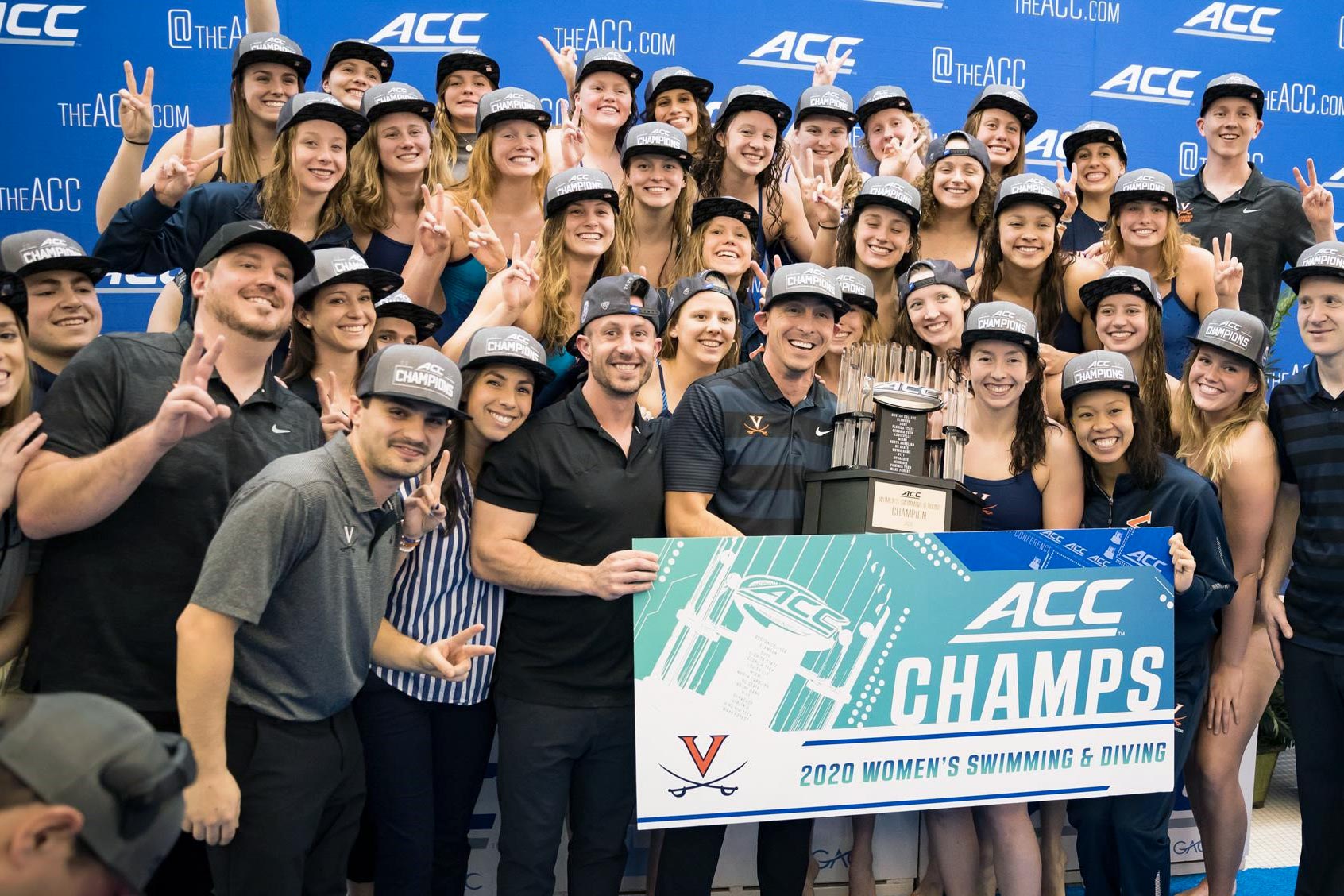 The Cavalier women’s swimming and diving team pose together holding the ACC trophy and a banner that reads ACC Champs 2020 Women's swimming & Diving