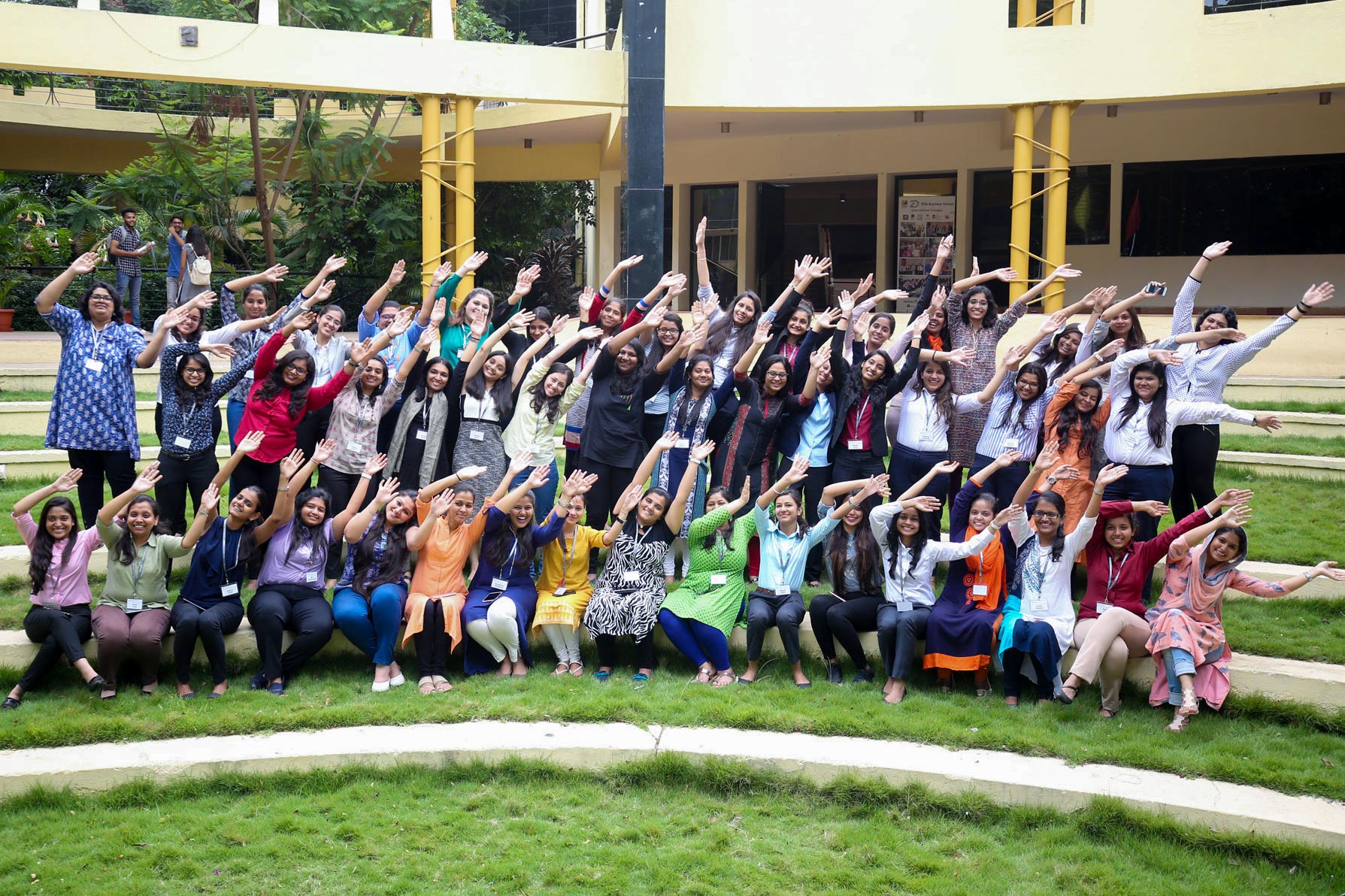 CFA Institute’s Young Women in Investment initiative take a group photo with their arms in the air leaning to the right of the image