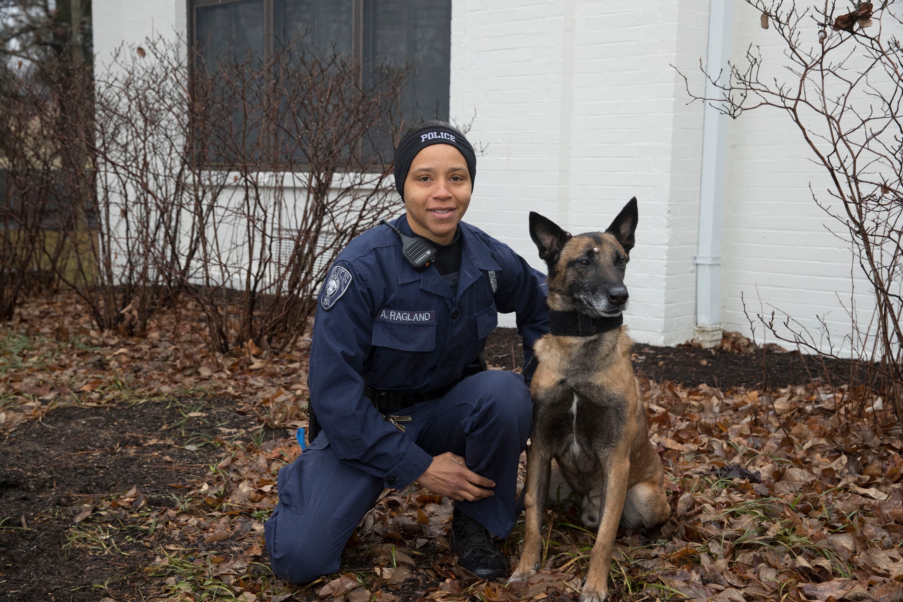 Officer Audrell Ragland and Muki sit in leaves together on Grounds