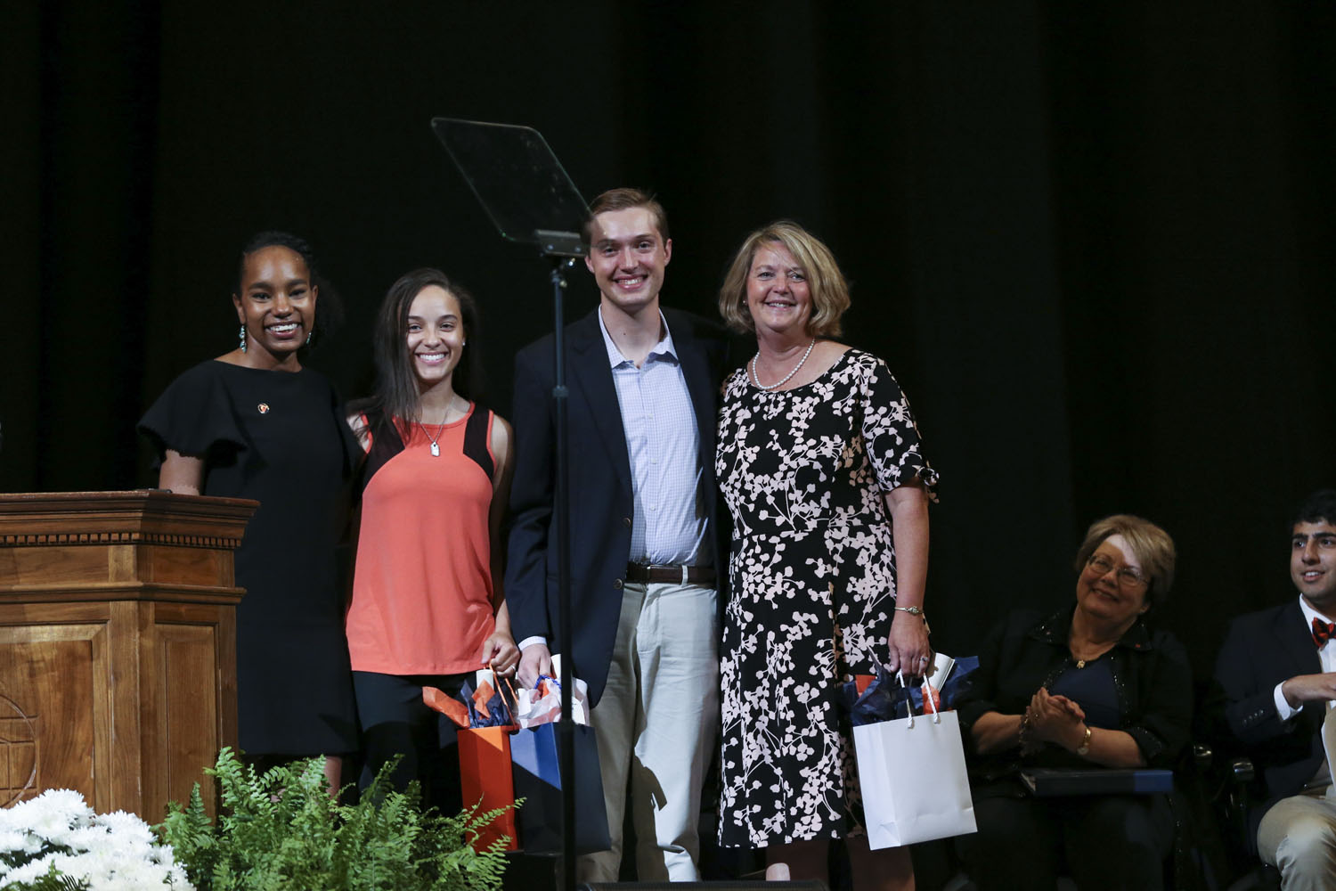 Standing for a group photo on stage.  Left to right: Bryanna F. Miller, left, Alysa M. Triplett, Jackson J.L. Nell, and Caroline “Carrie” Rudder.