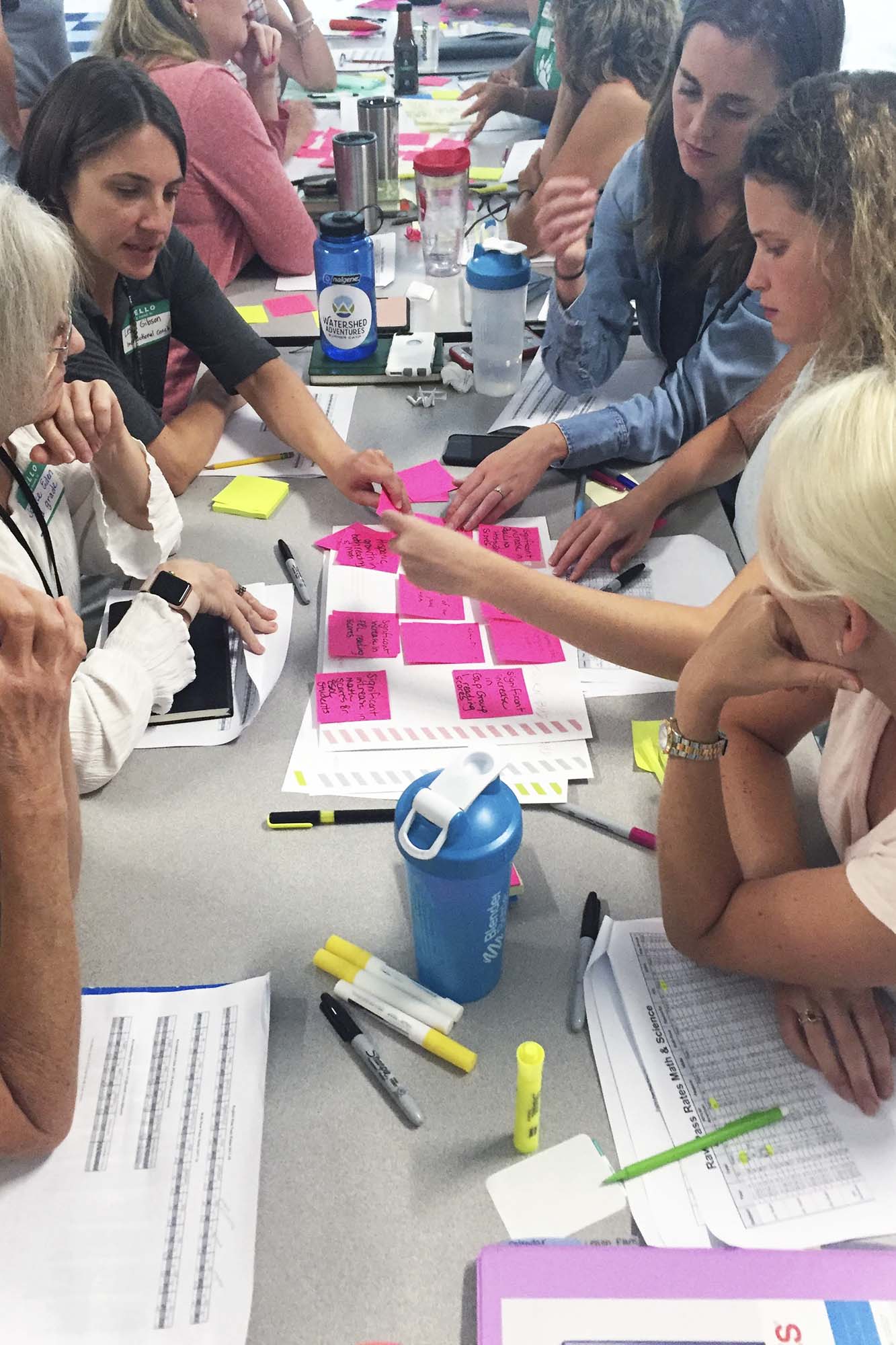 Group of people organizing pink sticky notes on a paper