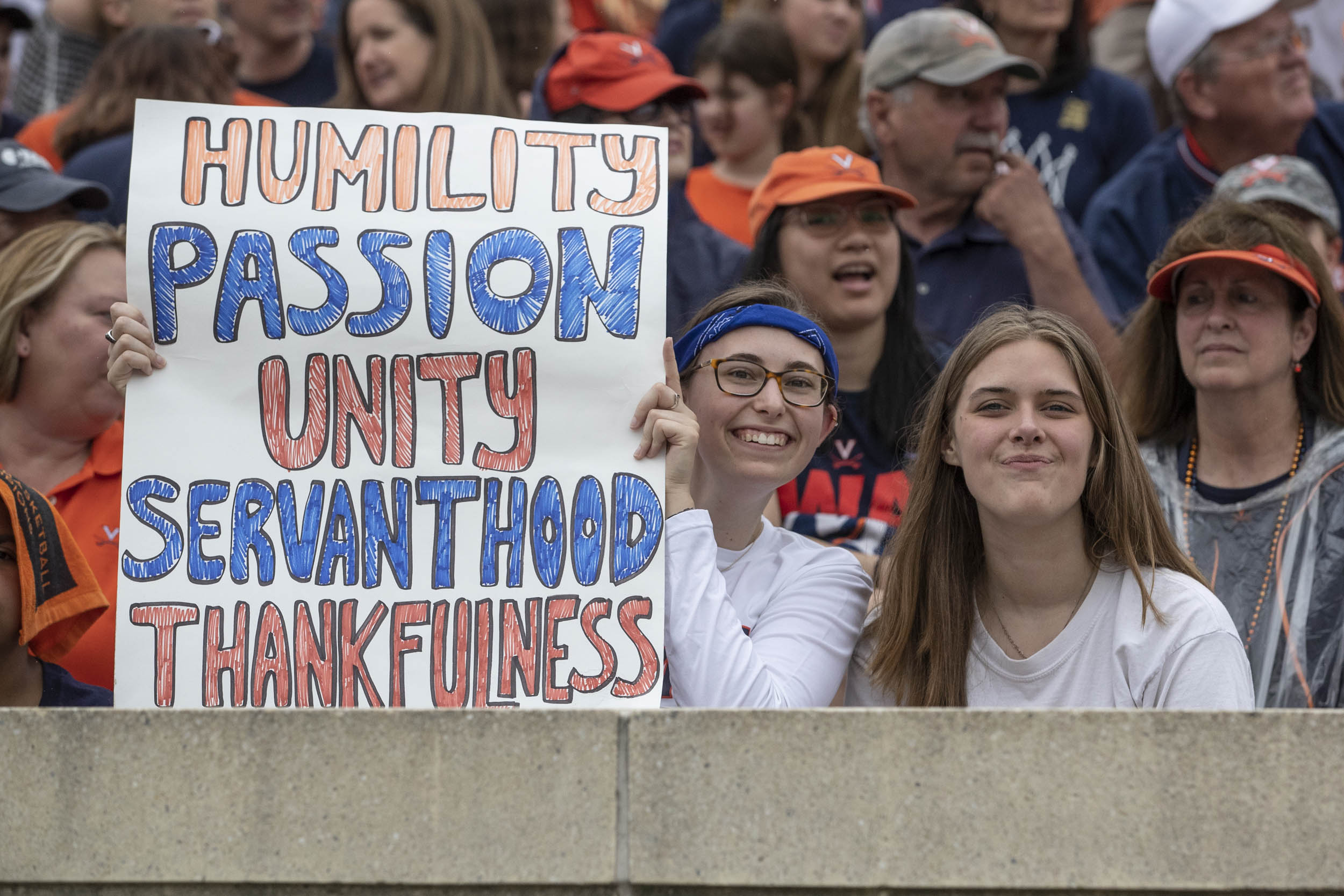 Fan holding a sign that reads: Humility passion unity servanthood thankfulness