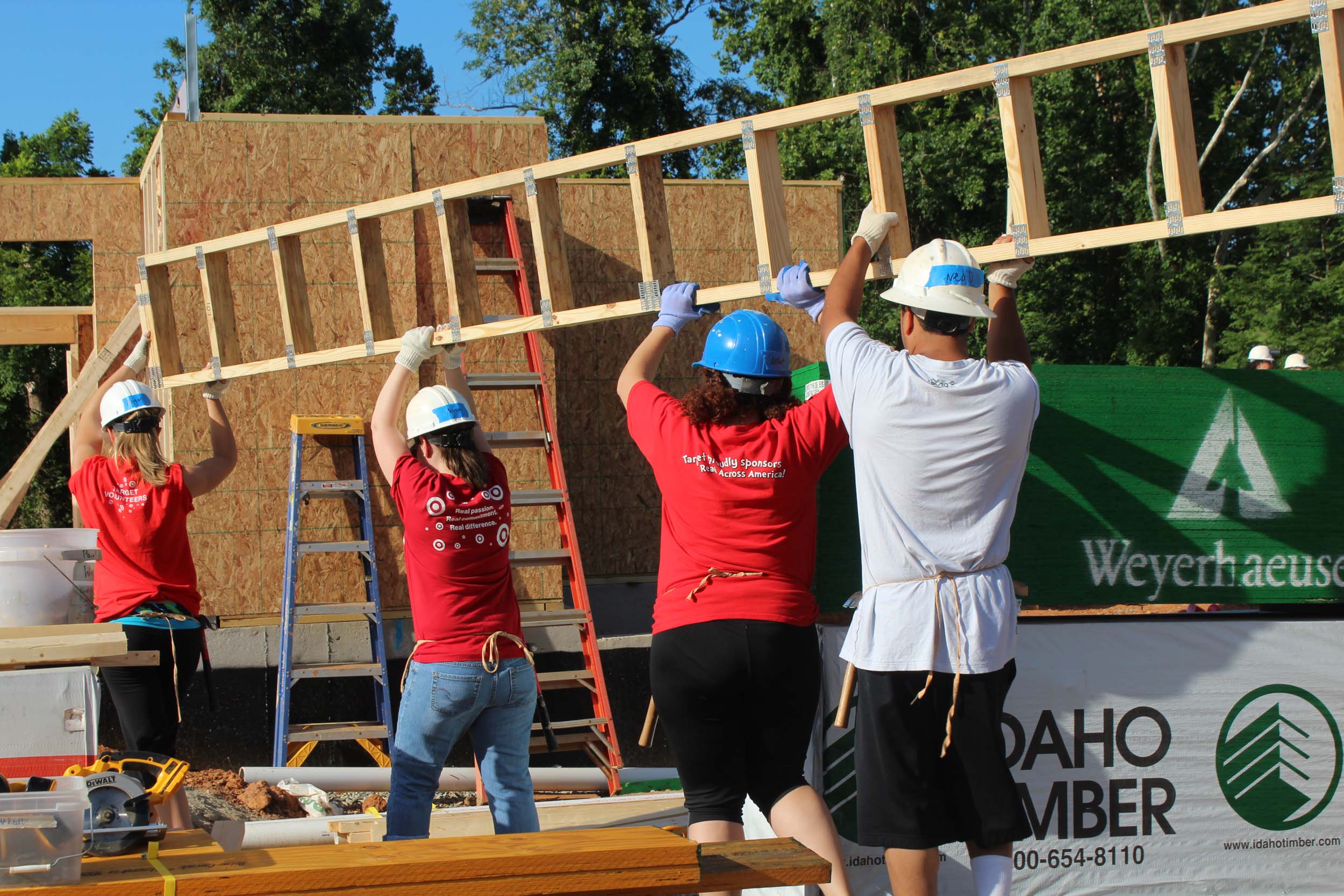Volunteers carry a wooden structure into a house that is being built