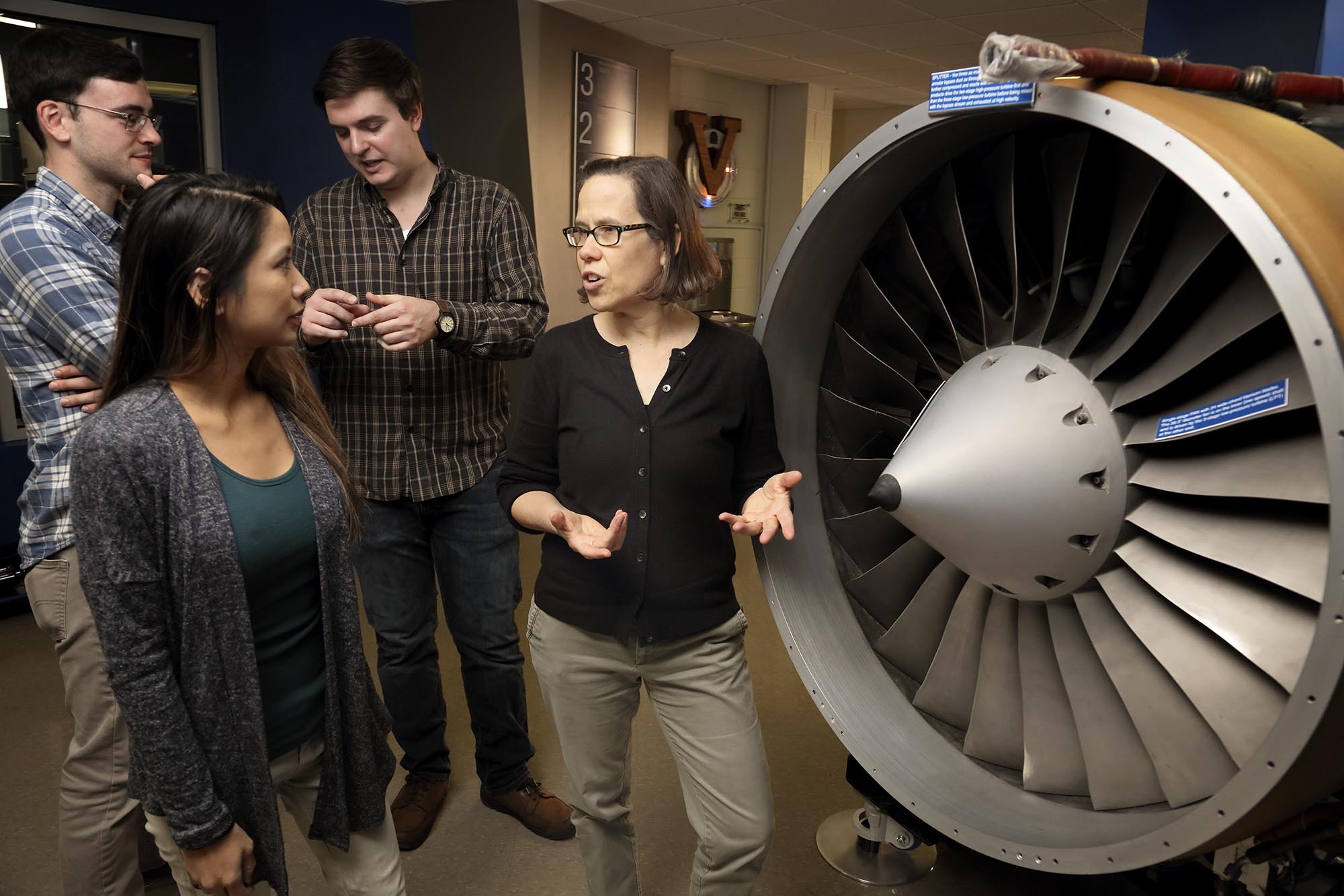 Elizabeth J. Opila speaking to students while looking at a an airplane engine