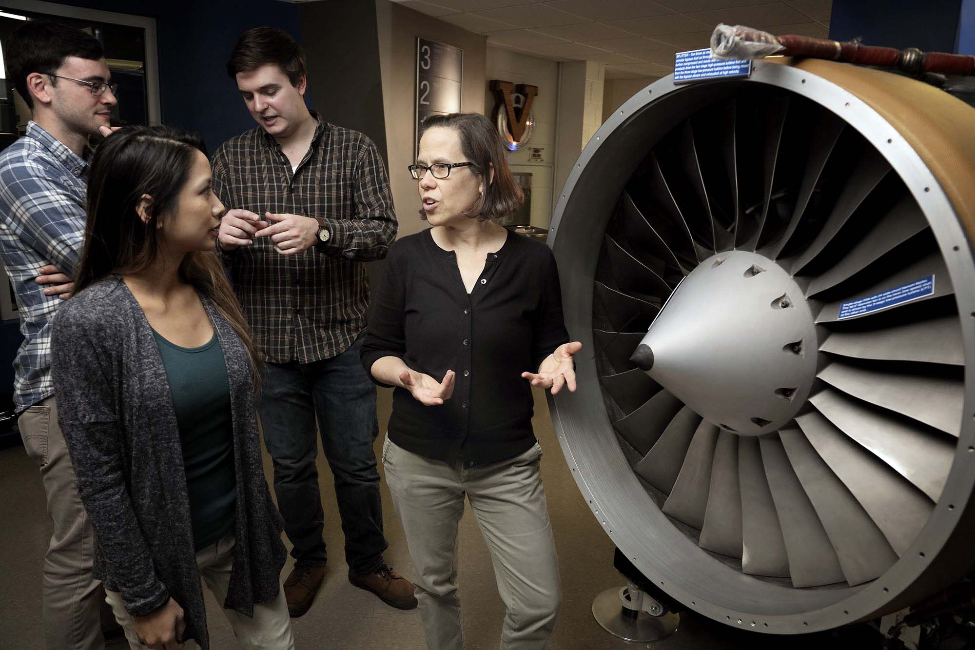 Elizabeth Opila speaking to students  in front of an airplane Engine