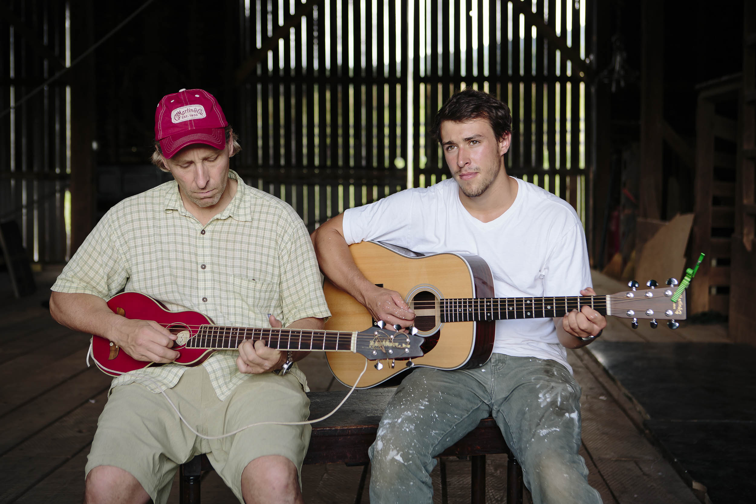 Bill and Will overman sitting on a bench together playing musical instruments