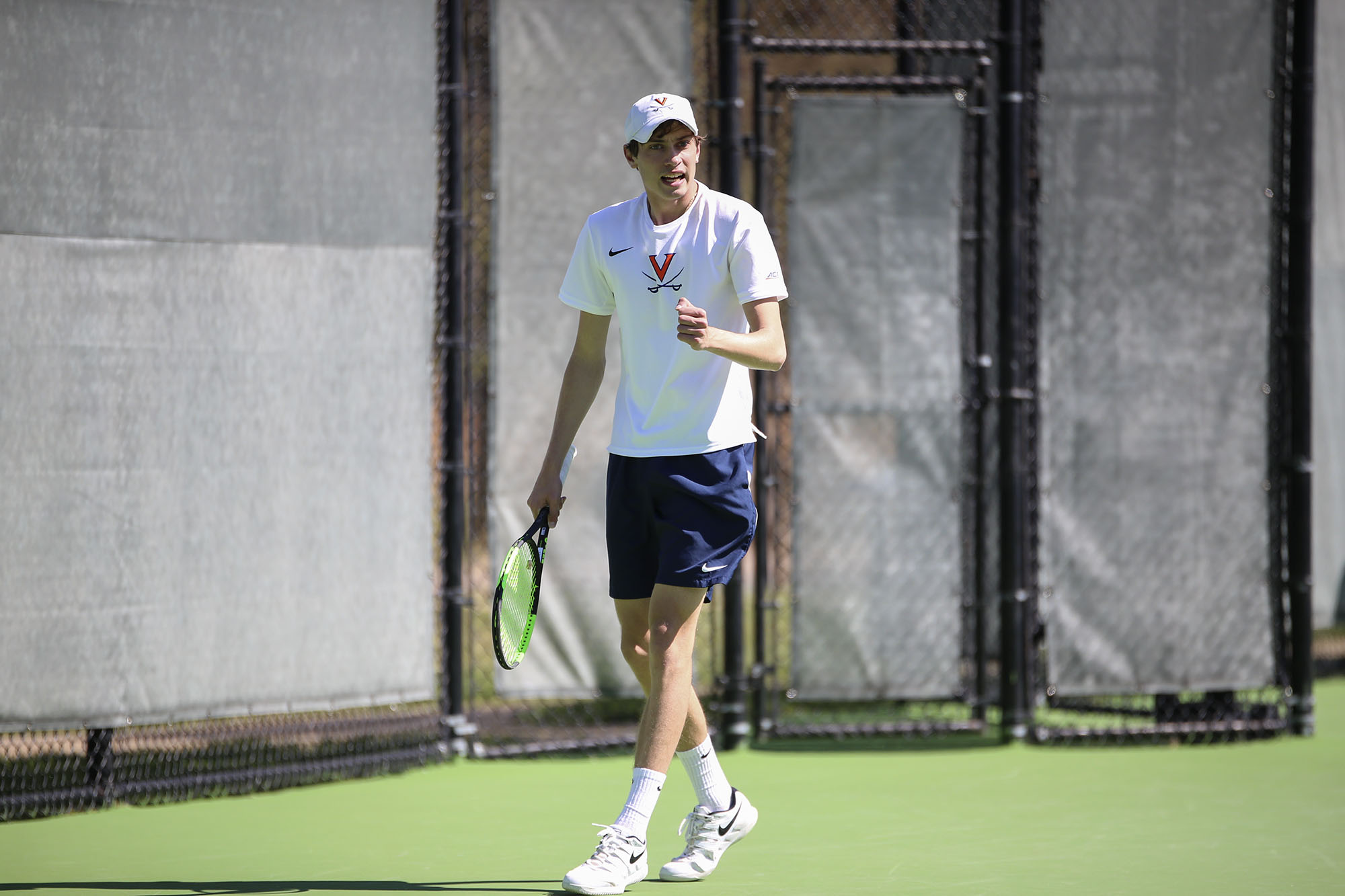 Spencer Bozsik carrying a tennis racquet on the court while talking