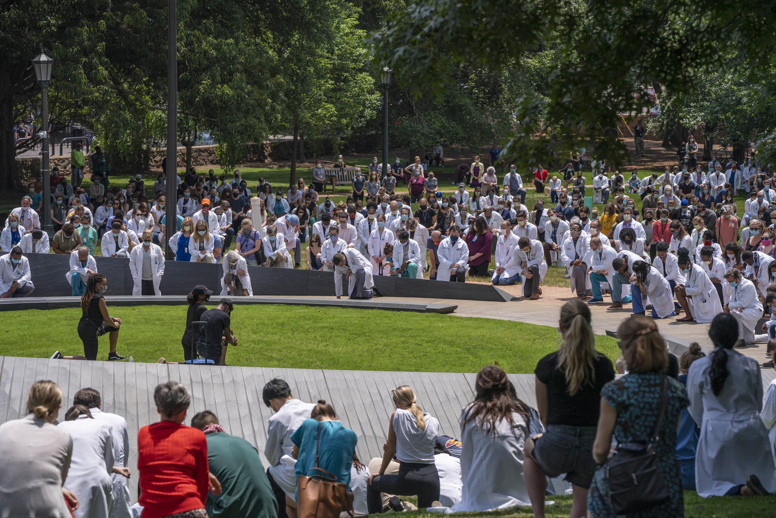 Hundreds of people kneel together at the Memorial for Enslaved Laborers 