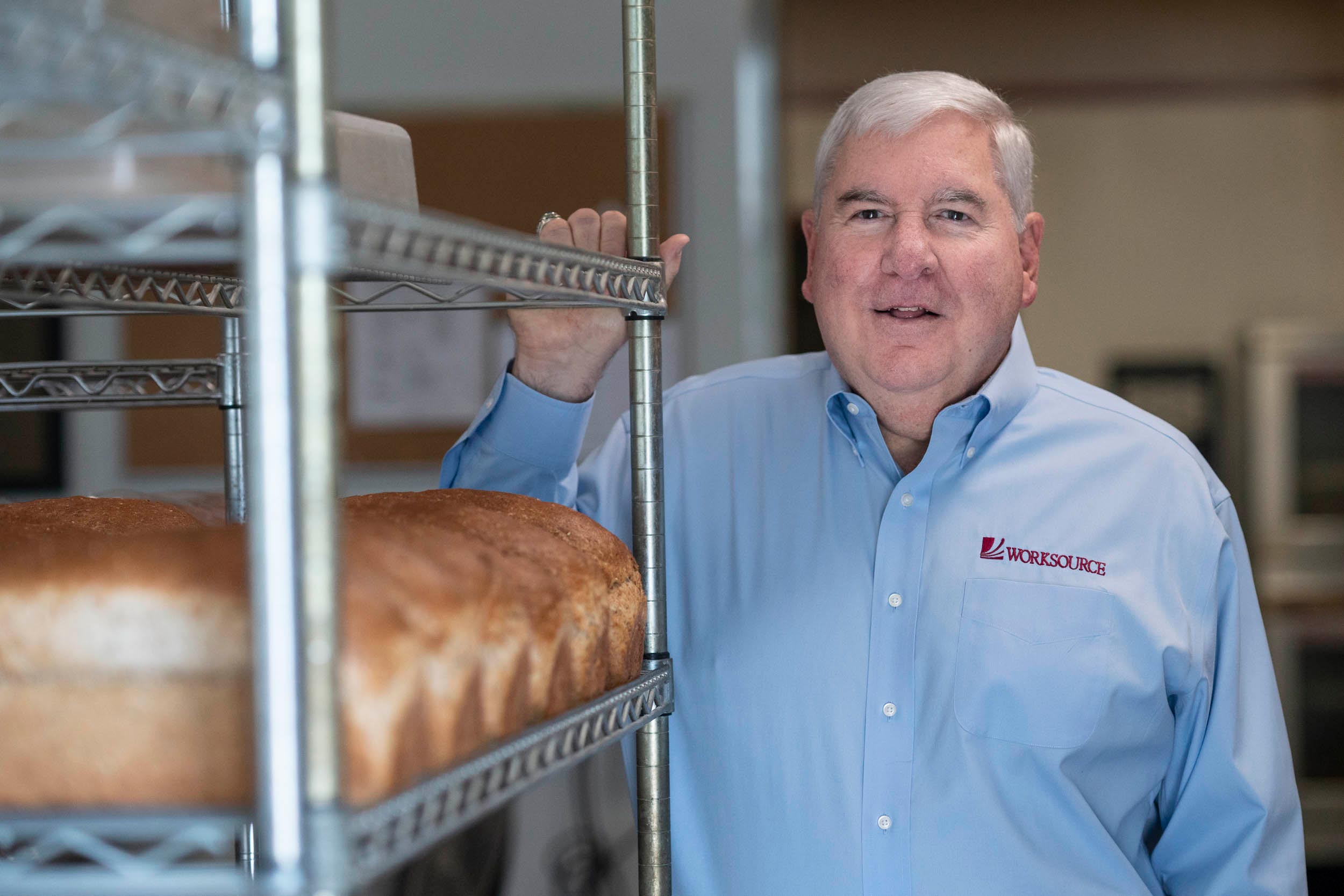 Chuck McElroy stands next to a shelf of bread