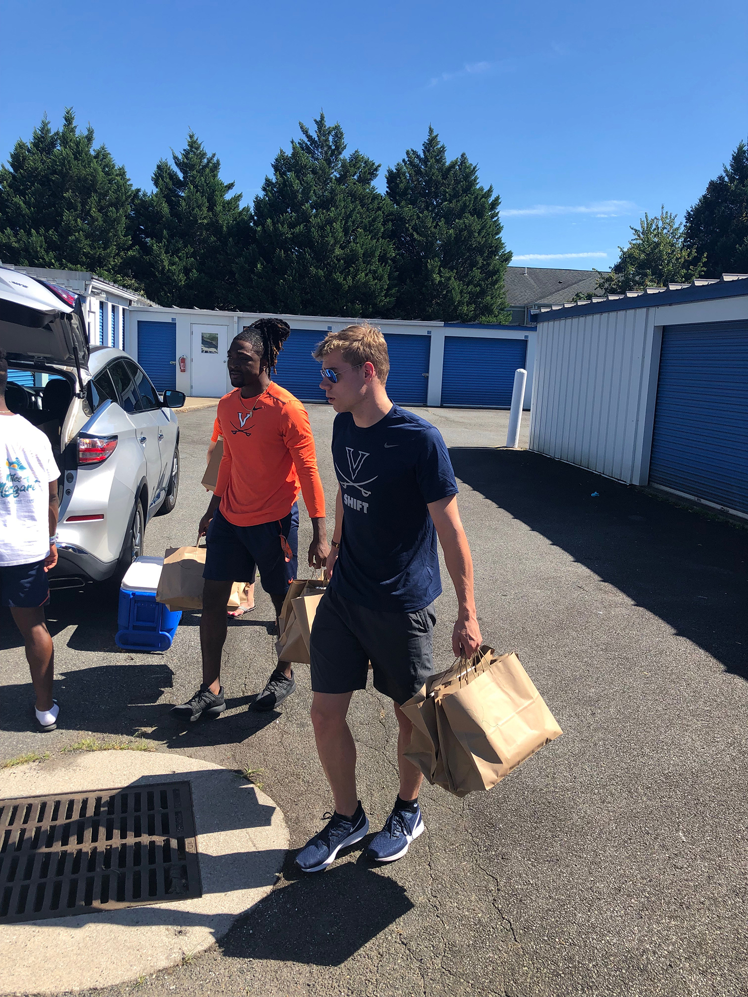 Bryce Perkins, left, and swimmer Henry Schutte carry bags of books to a car