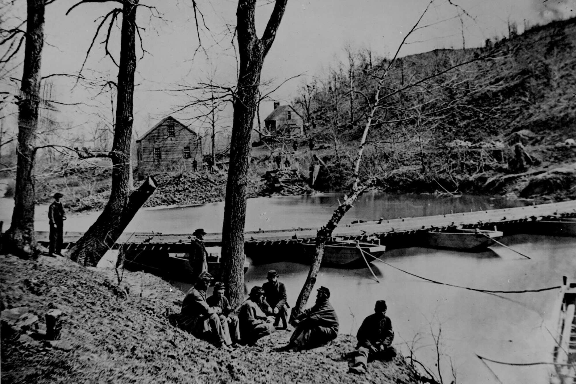 Black and white photo of A pontoon bridge at Bull Run, Virginia with soldiers sitting on bank