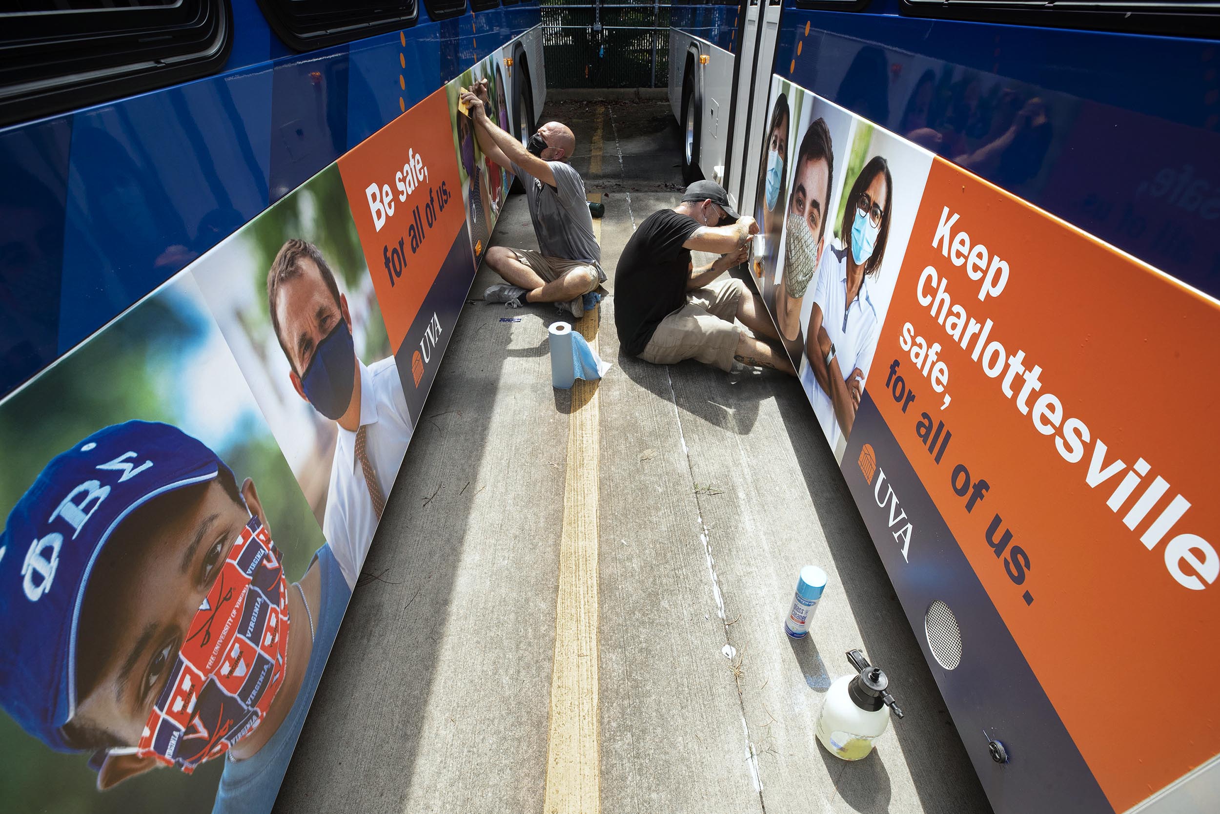 UVA Staff members working on placing signs on the outside of the busses