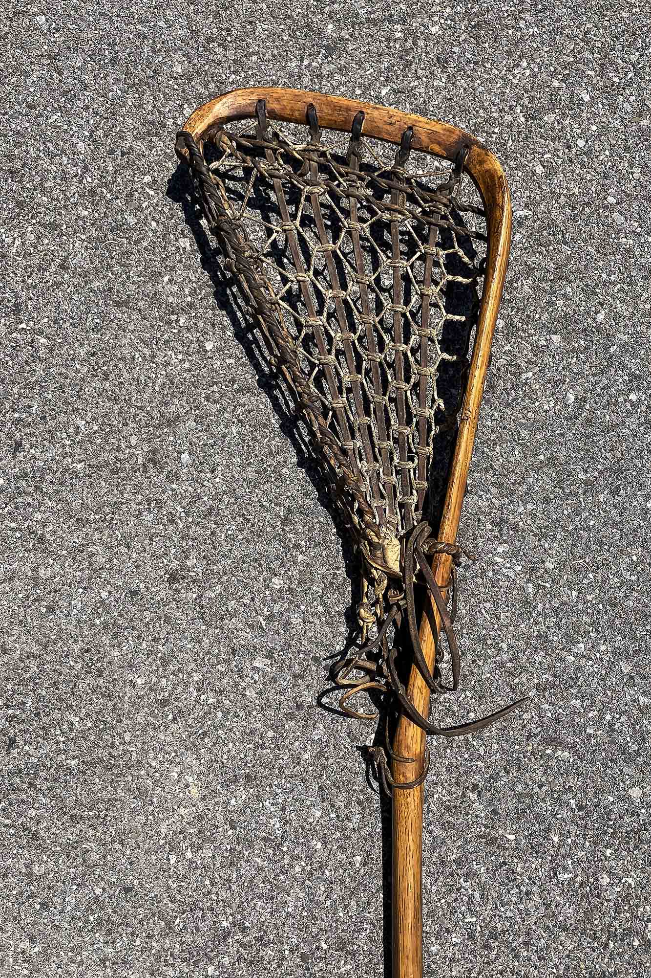 Up close view of a Lacrosse stick made from wood and old leather