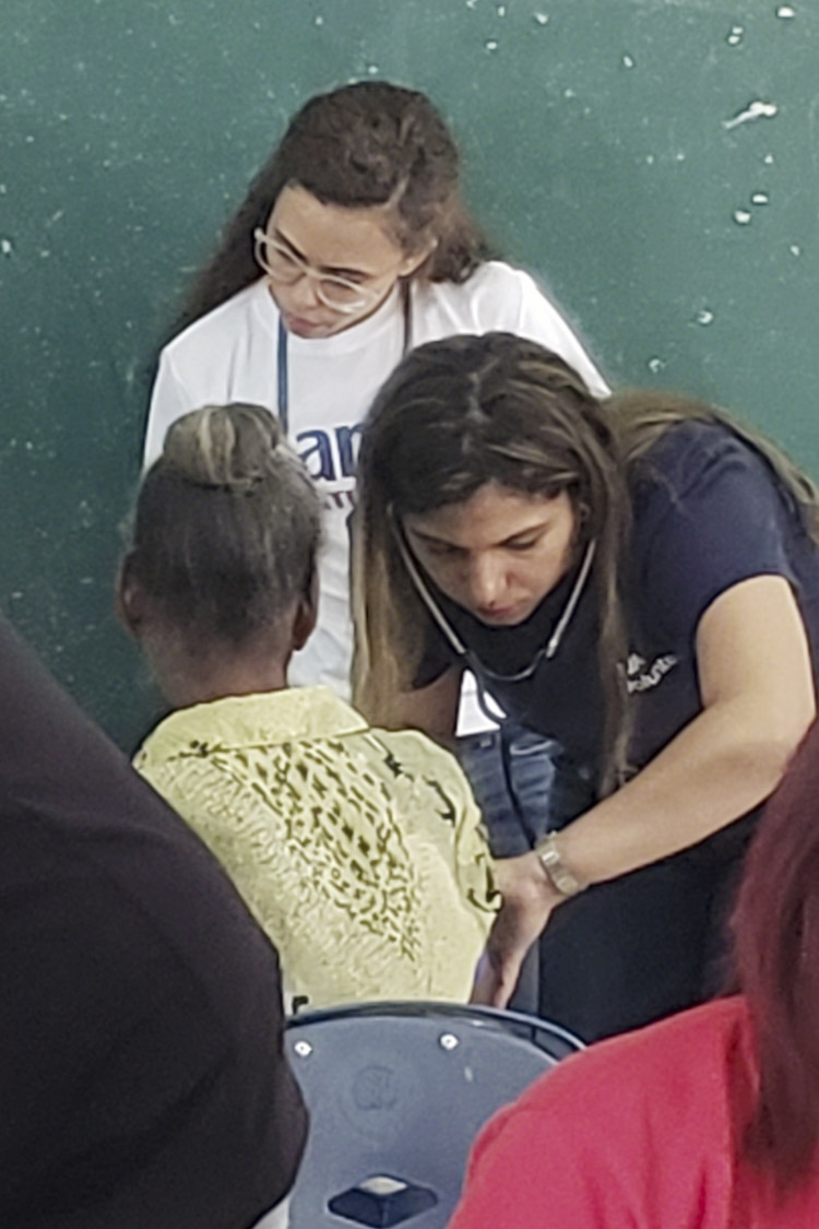 Eliany Mejia-Lopez takes the blood pressure of a child