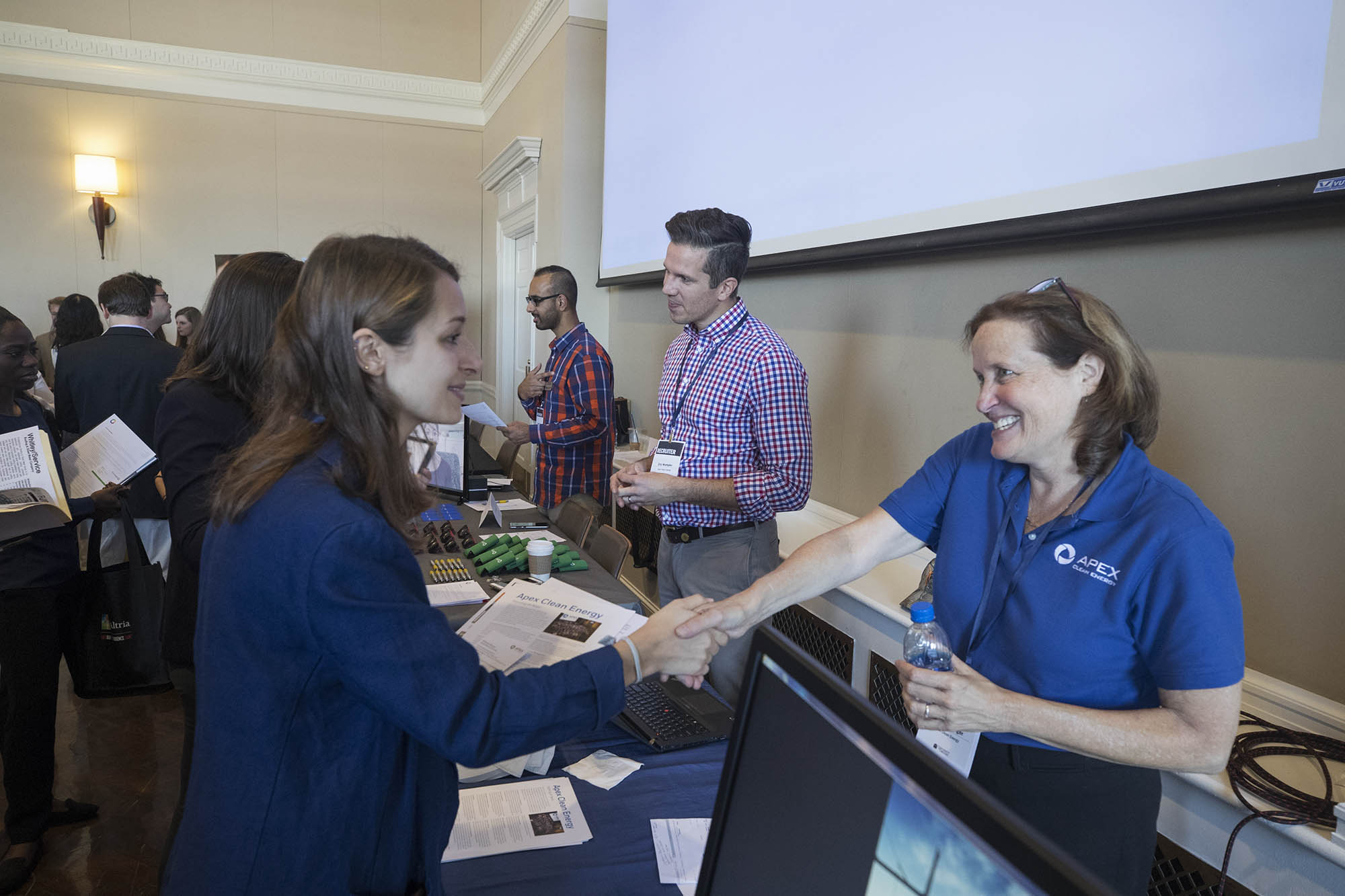 Student shaking the hand of a Merck Representative at their table during a career fair