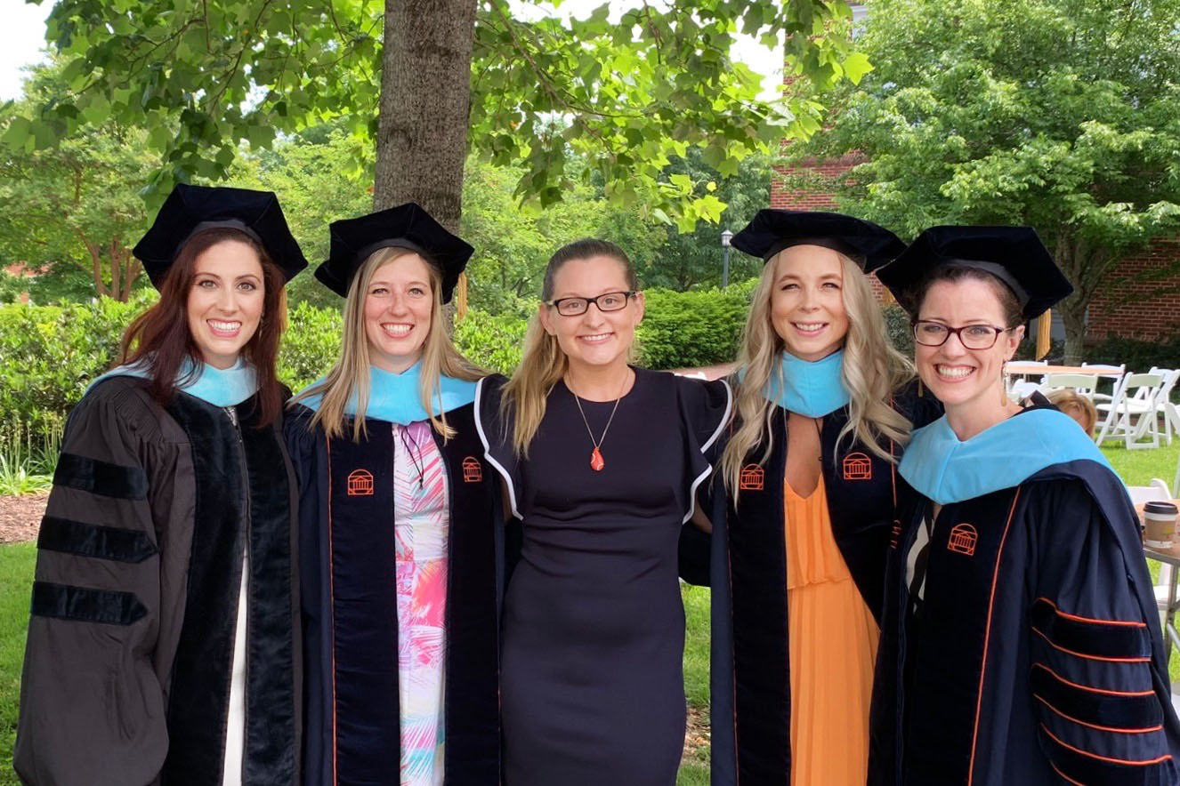 Thomas, middle, stands with four graduates, two on each side