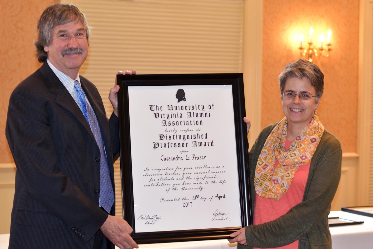 Cassandra Fraser, right, stands with a man while they hold a distinguished professor award that she won