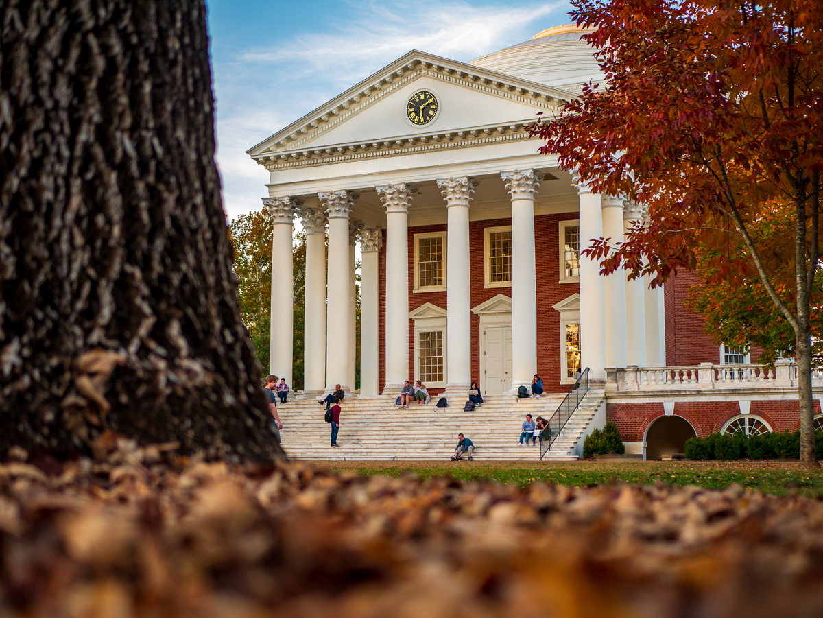 Rotunda with students sitting on the steps and the base of a tree on the left of the picture