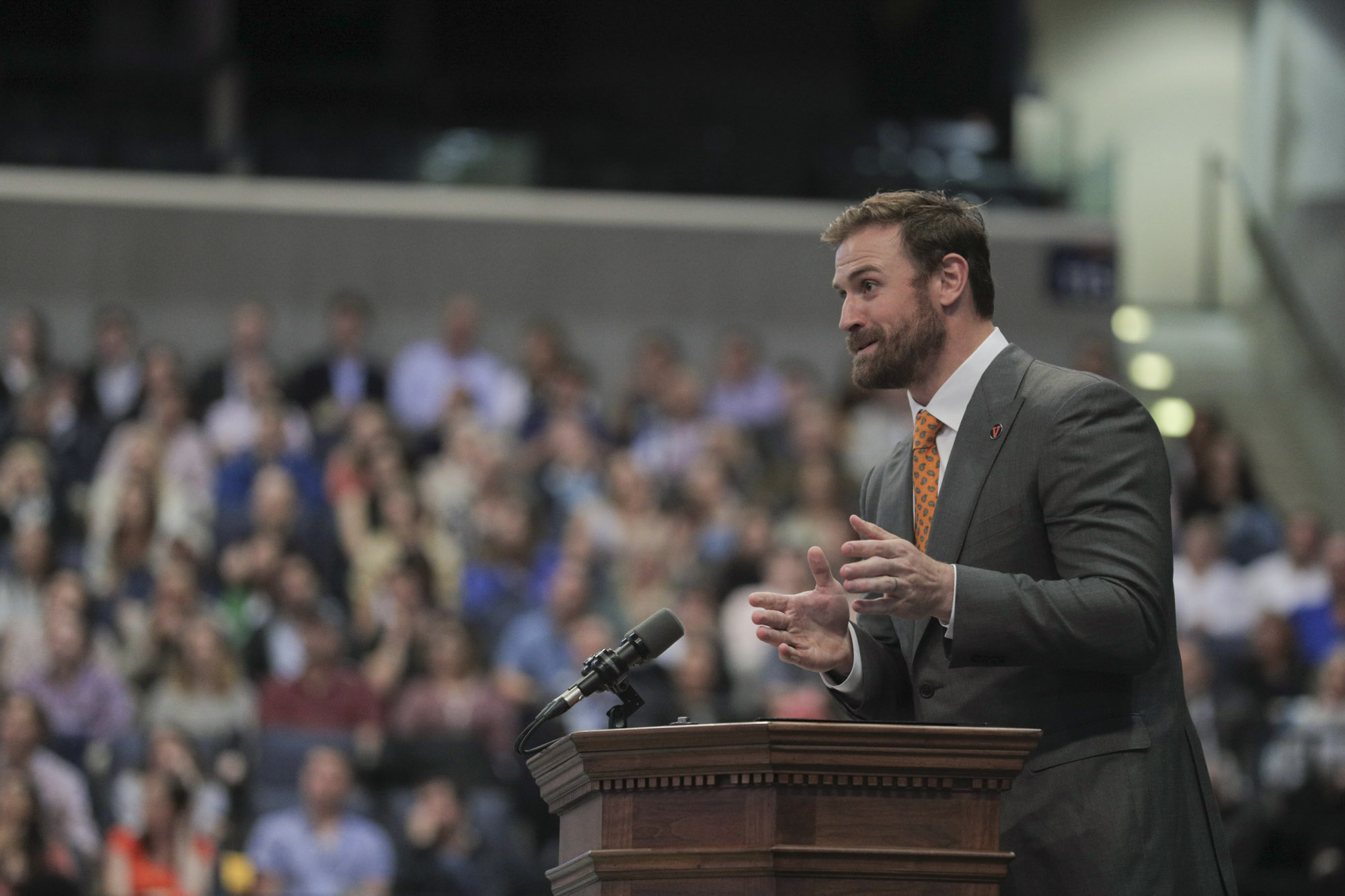 Chris Long stands at a podium giving a speech in front of a crowd