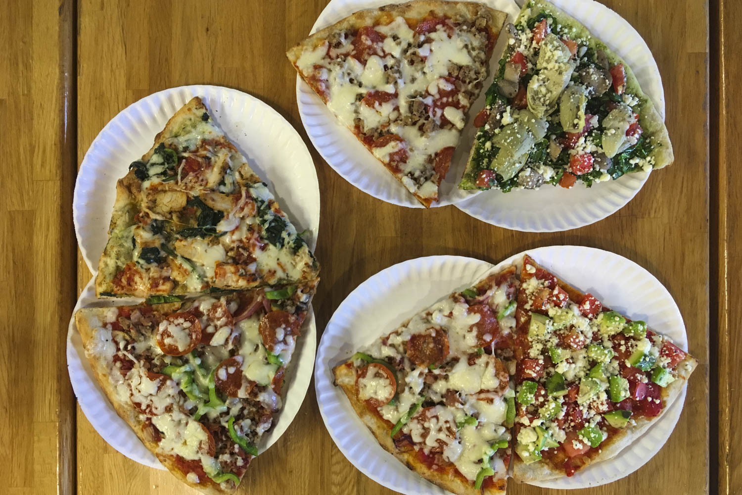 Various kinds of pizza on paper plates