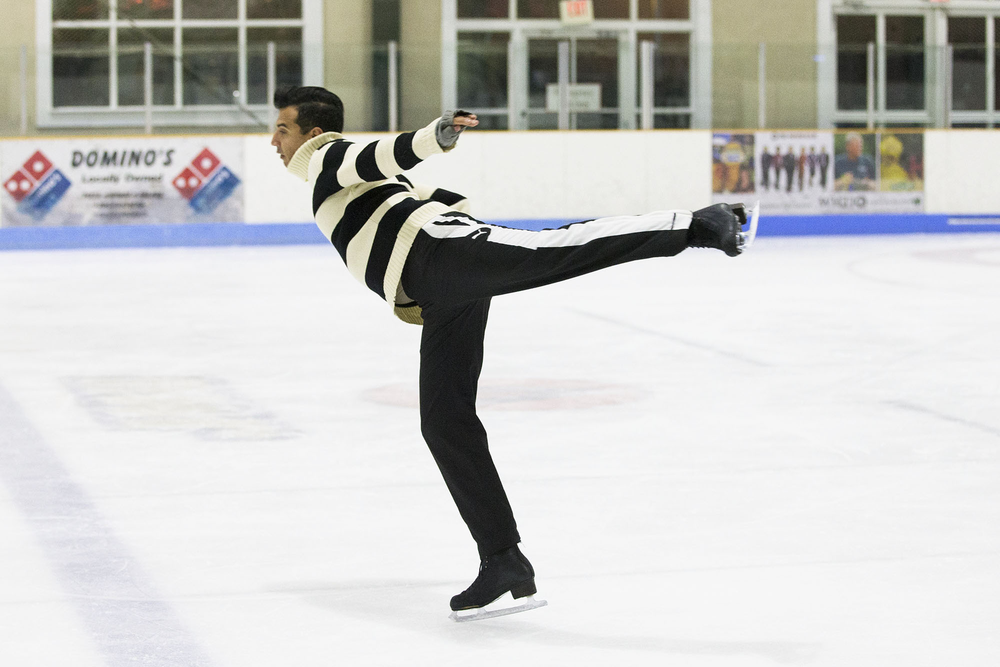Christopher Ali skating on the ice with one leg raised and arms spread apart
