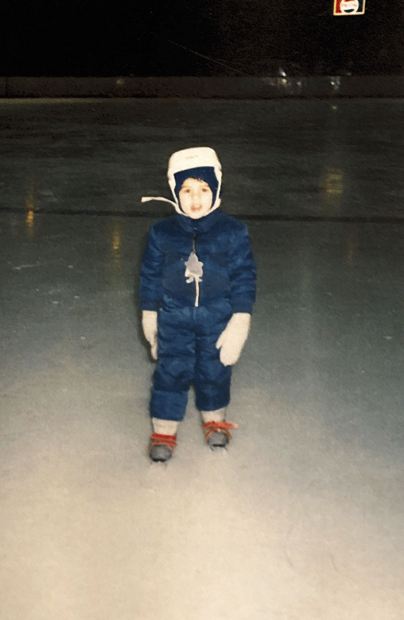 Christopher Ali as a child in a puffy suit and in skates on the ice