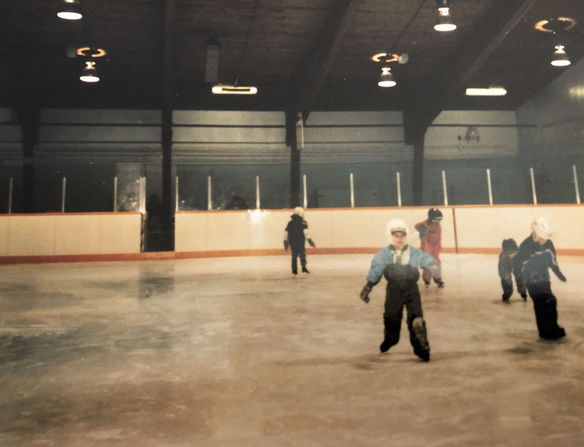 Christopher Ali and 4 friends dressed in warm clothing skating on the ice as children
