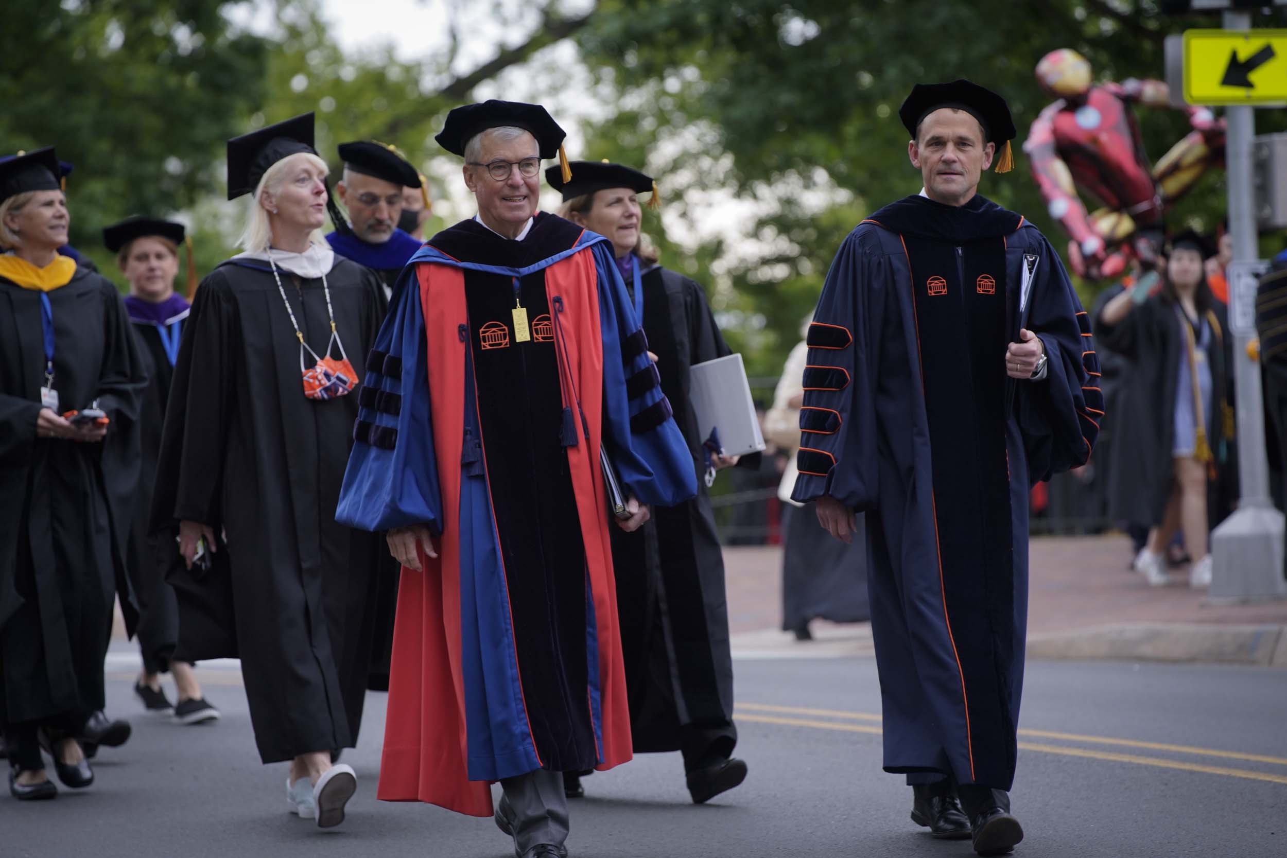 President Jim Ryan and other UVA Leadership walking in their Graduation robes down a road in Grounds