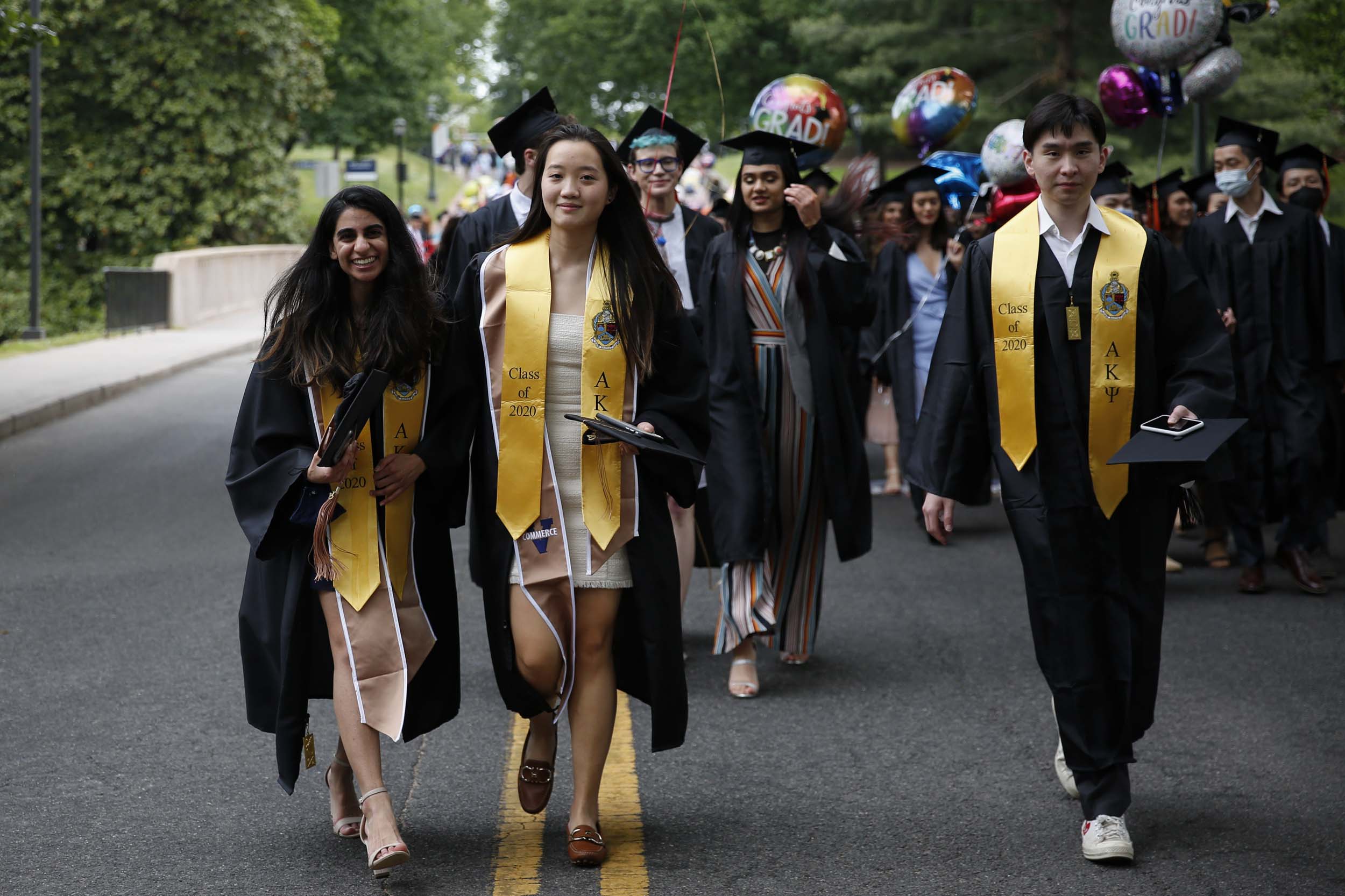 UVA graduations walk in their robes down the road carrying balloons