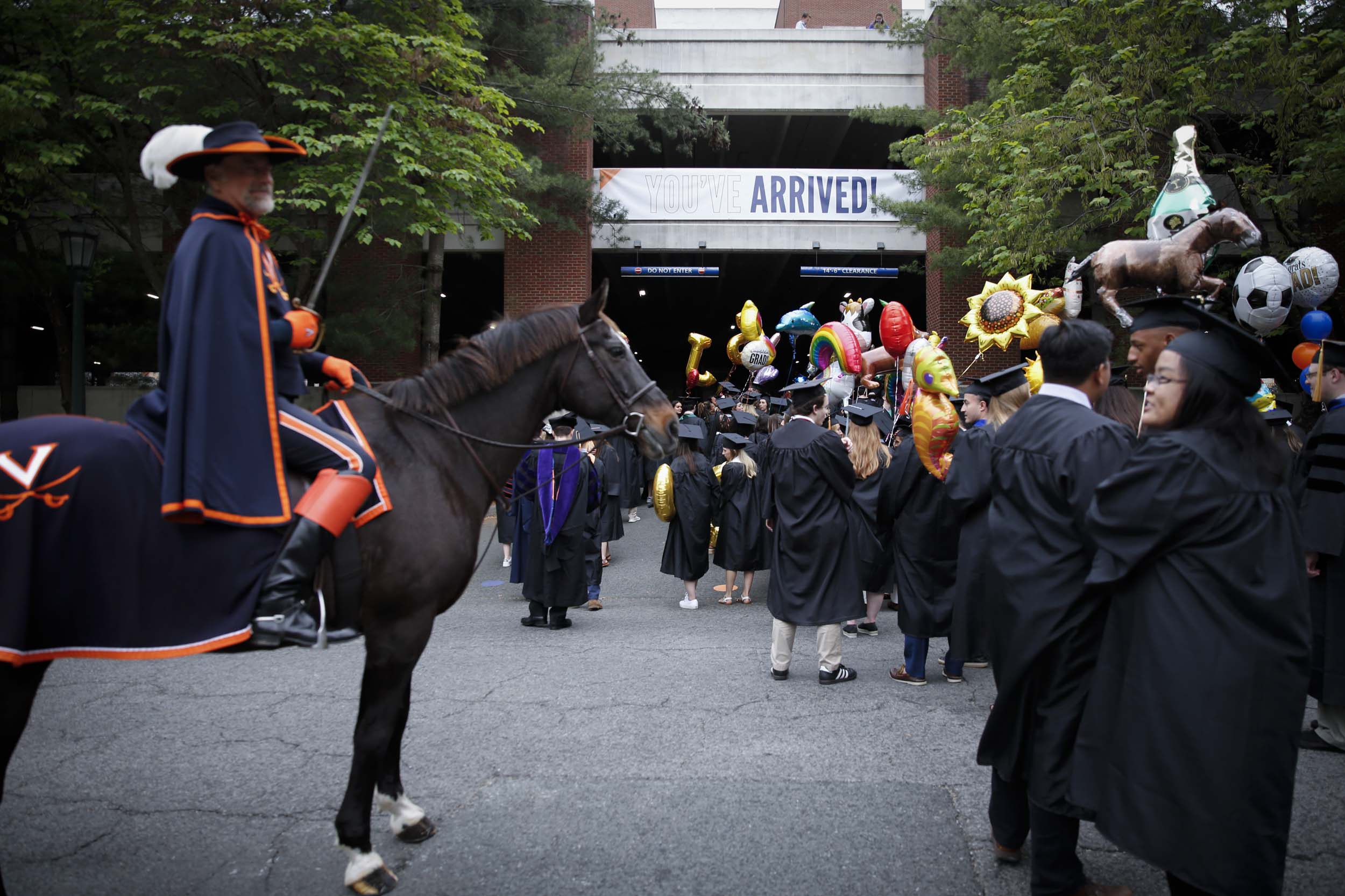 Graduates walking into final exercises with a Cavalier on a horse watching