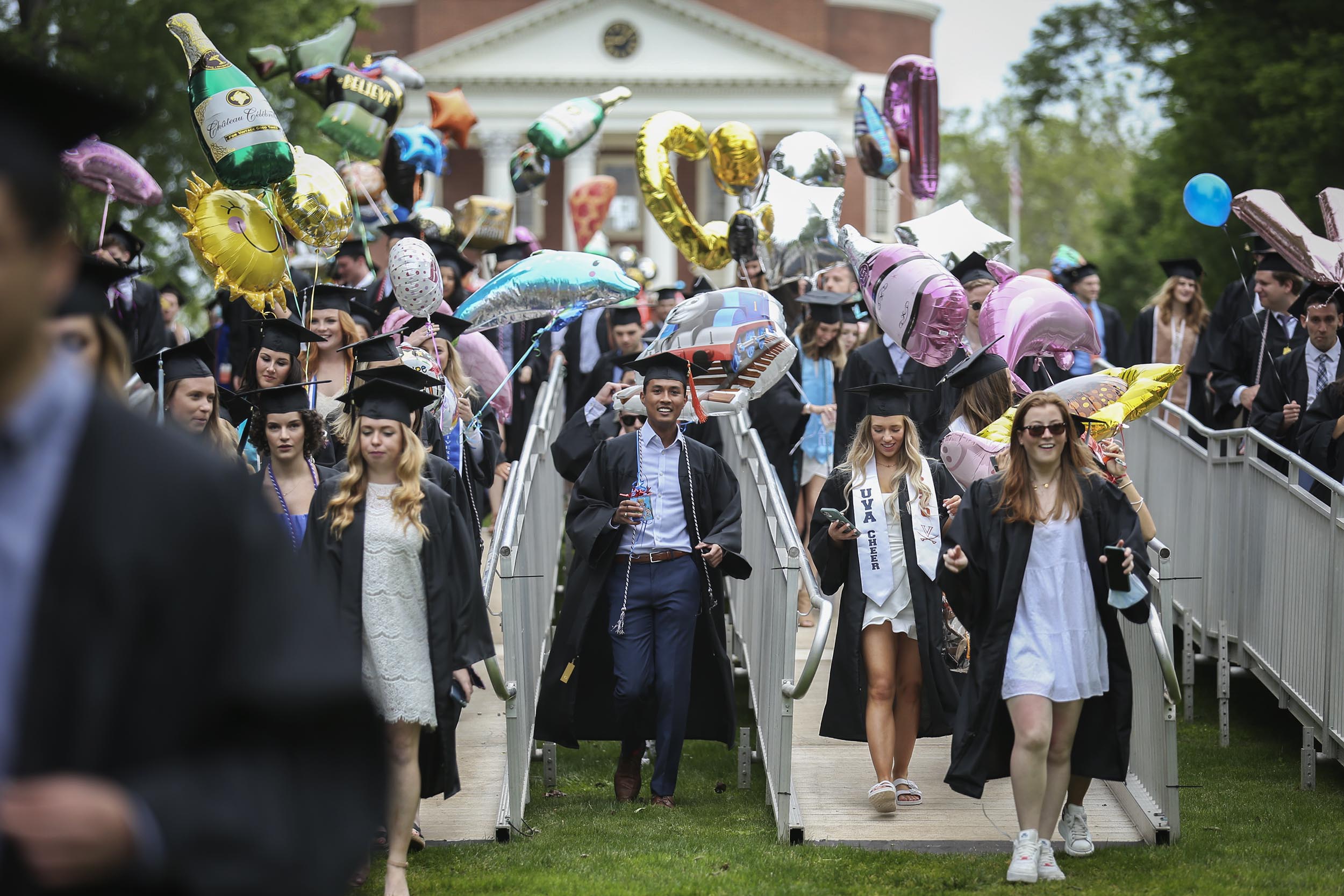 Graduates walking down ramps carrying various balloons